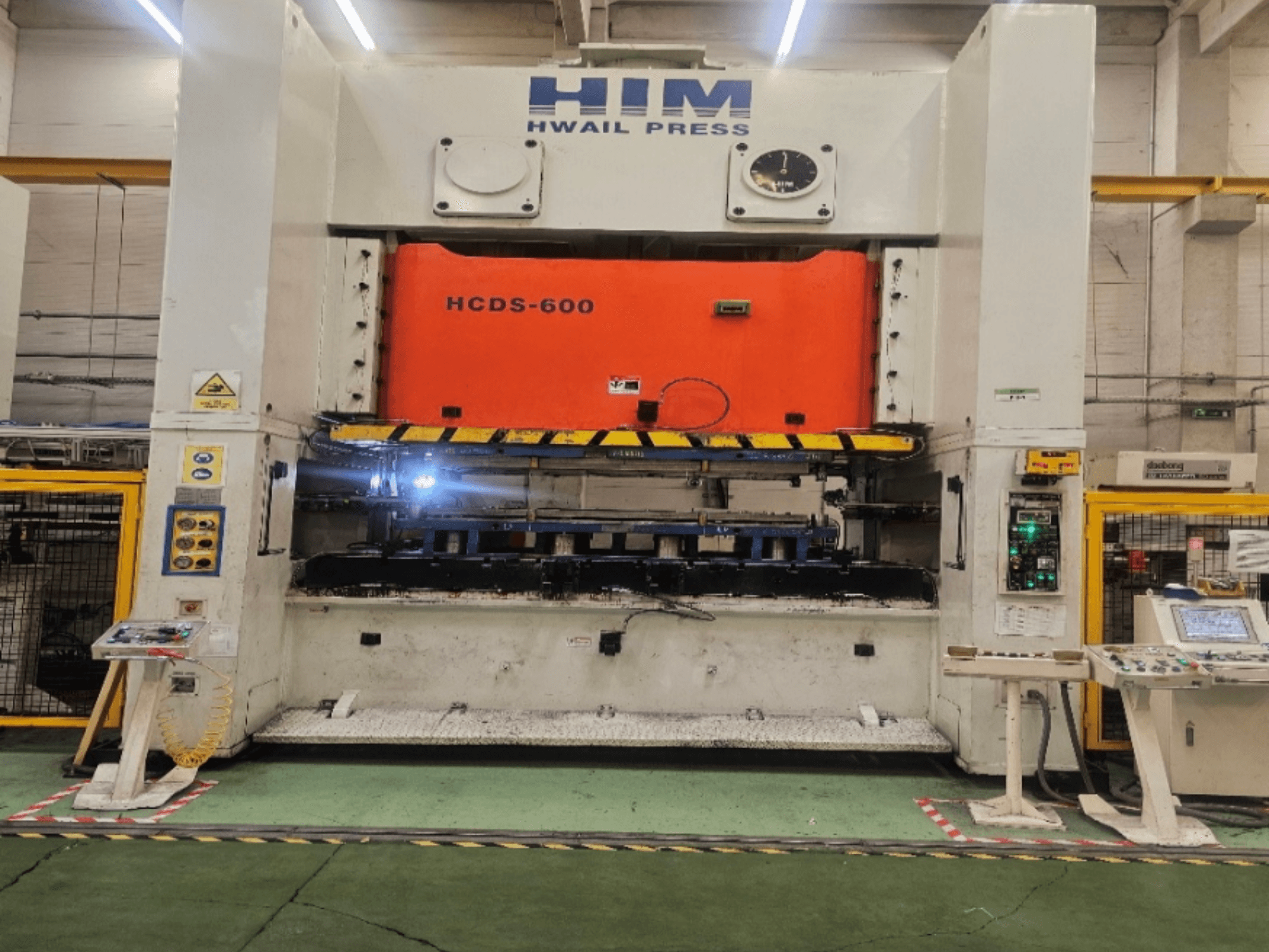 Vista frontal da prensa mecânica de estampagem HIM HWAIL PRESS HCDS-600, com uma placa de prensagem e um painel de controlo na cor laranja.