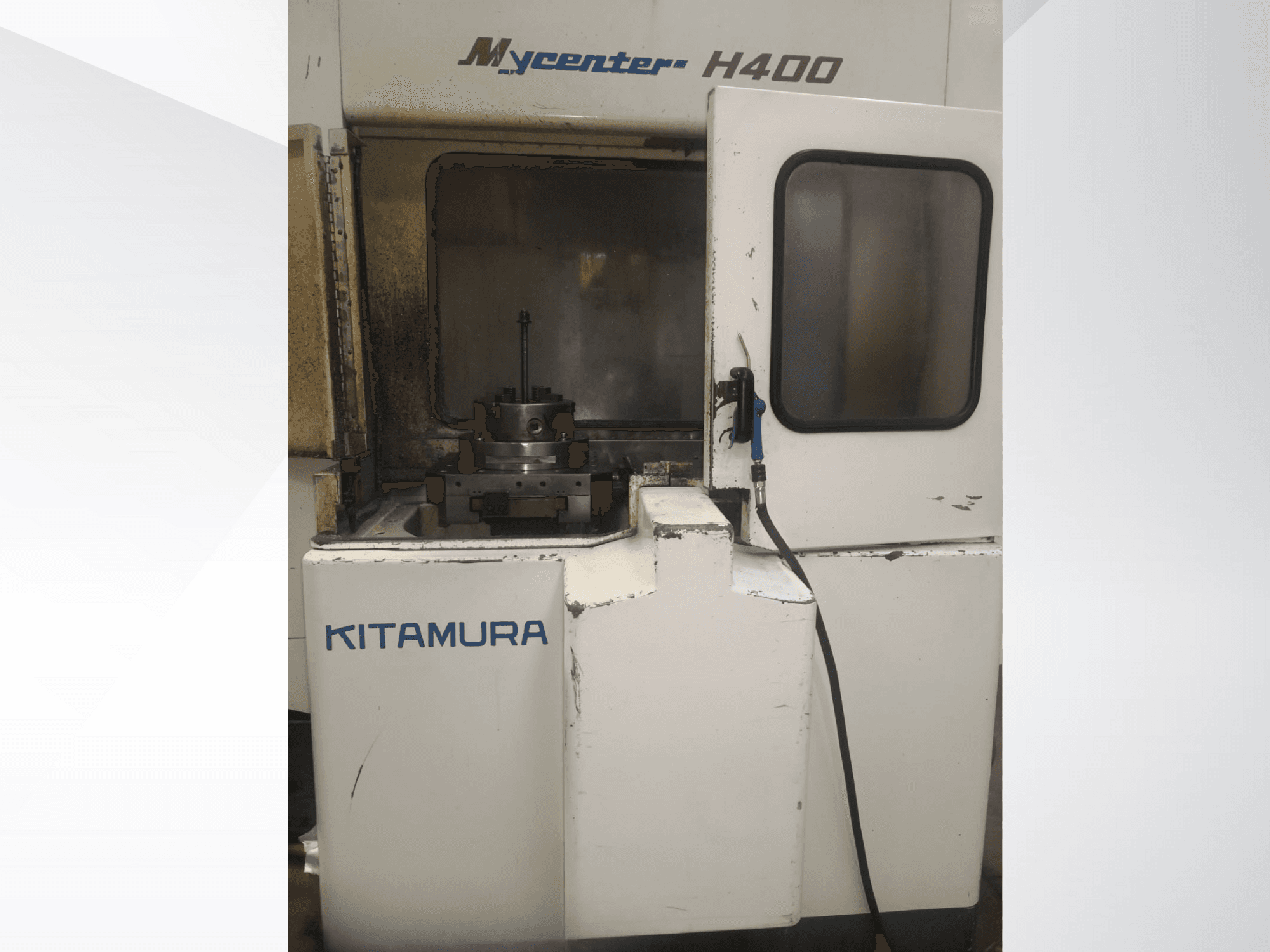 Máquina CNC Kitamura Mycenter H400, vista frontal, com área de trabalho e painel de controlo visíveis, com sinais de utilização.