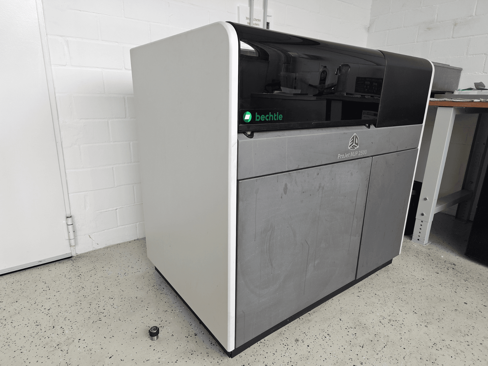 Impressora 3D de plástico ProJet MJP 2500 Plus da 3D Systems, vista de frente; apresenta um design elegante, com a parte superior escura e o corpo claro.