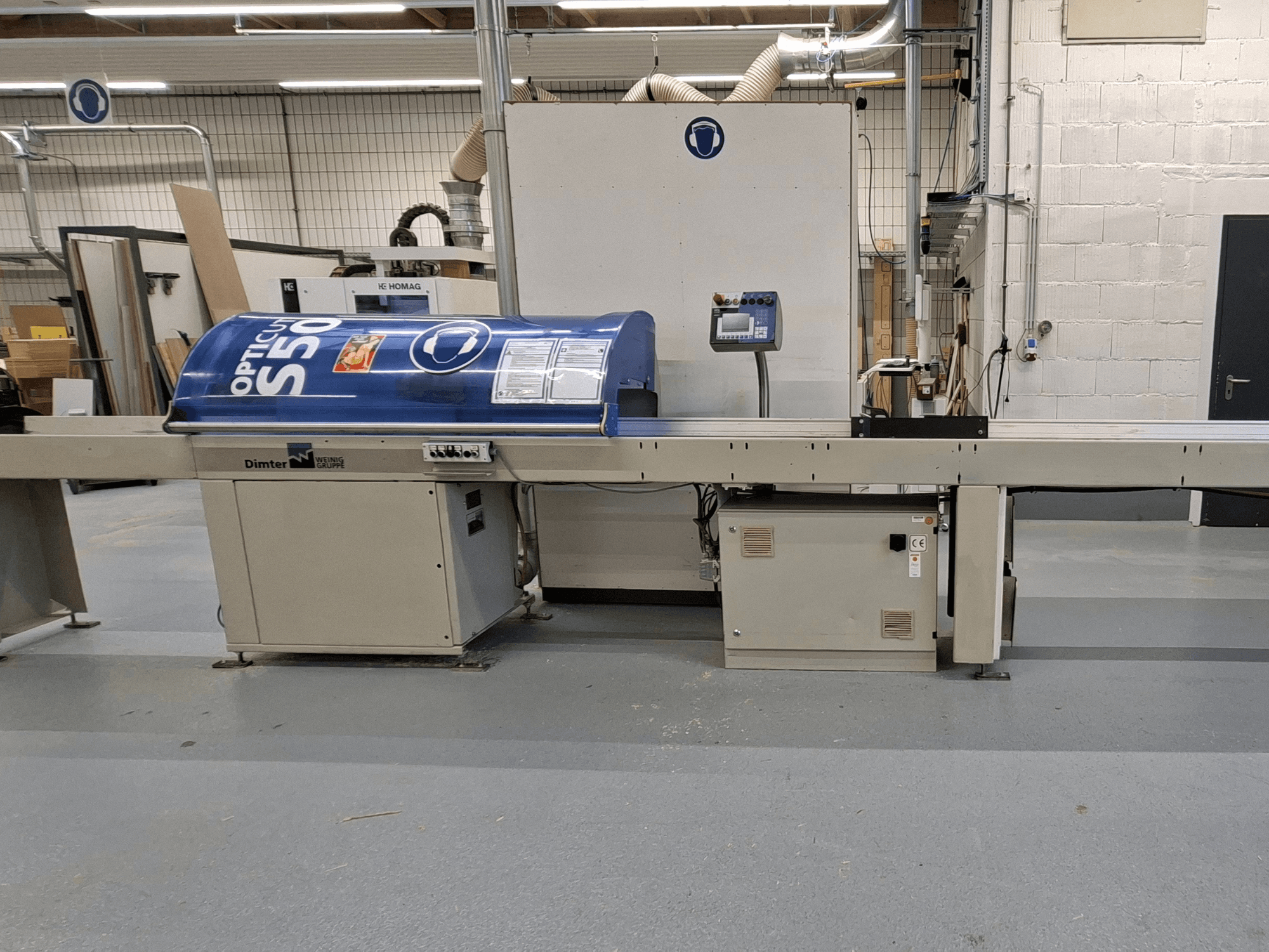 Máquina de corte de madeira Dimter OptiCut S50 em vista lateral, com uma caixa azul, painel de controlo e tapete transportador.