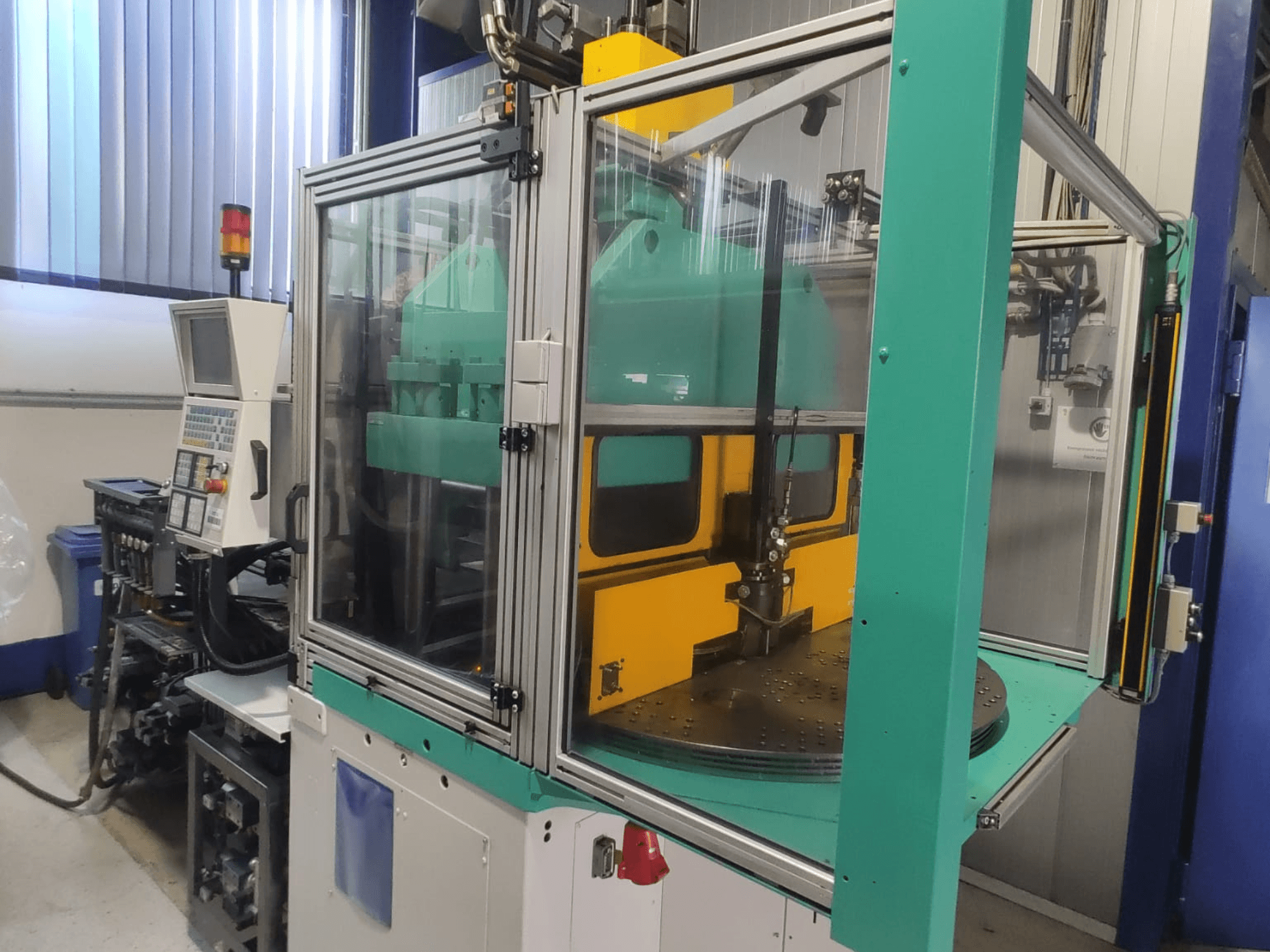 Máquina de moldagem por injeção vertical Arburg 1200 TS 800-60-350, vista frontal que mostra o painel de controlo e a estrutura de proteção.