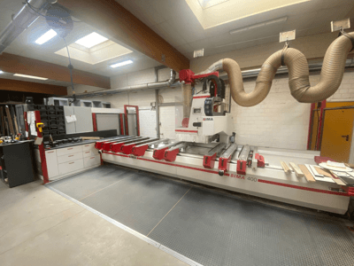 Máquina CNC BIMA 400 vista de frente, com um design vermelho e branco e um sistema de extração de poeiras.