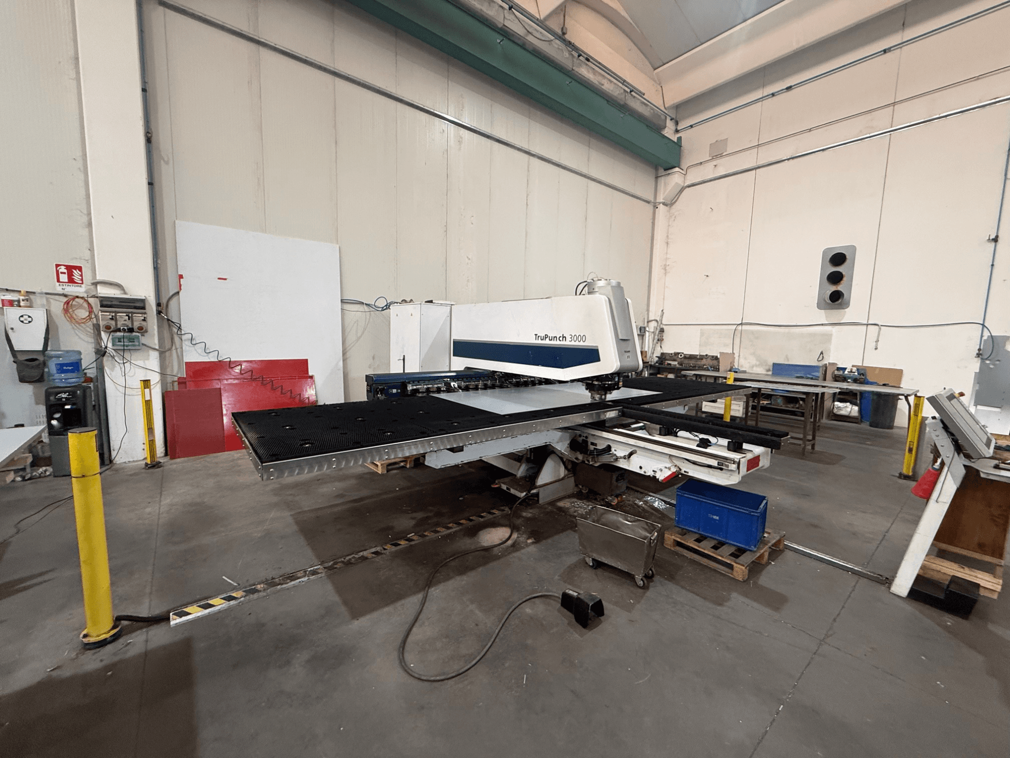 Máquina de perfuração CNC TRUMPF TruPunch 3000, vista lateral, mostrando a cabeça de perfuração, a mesa de grandes dimensões e o ambiente da oficina em redor.