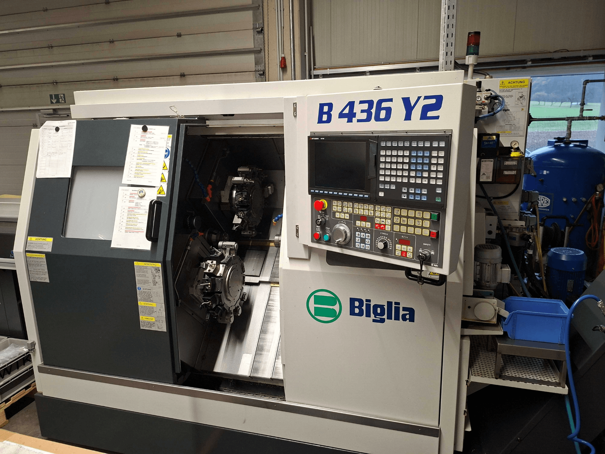 Torno CNC Biglia B 436 Y2 em vista lateral, com dois fusos e painel de controlo com botões e visor para operações.