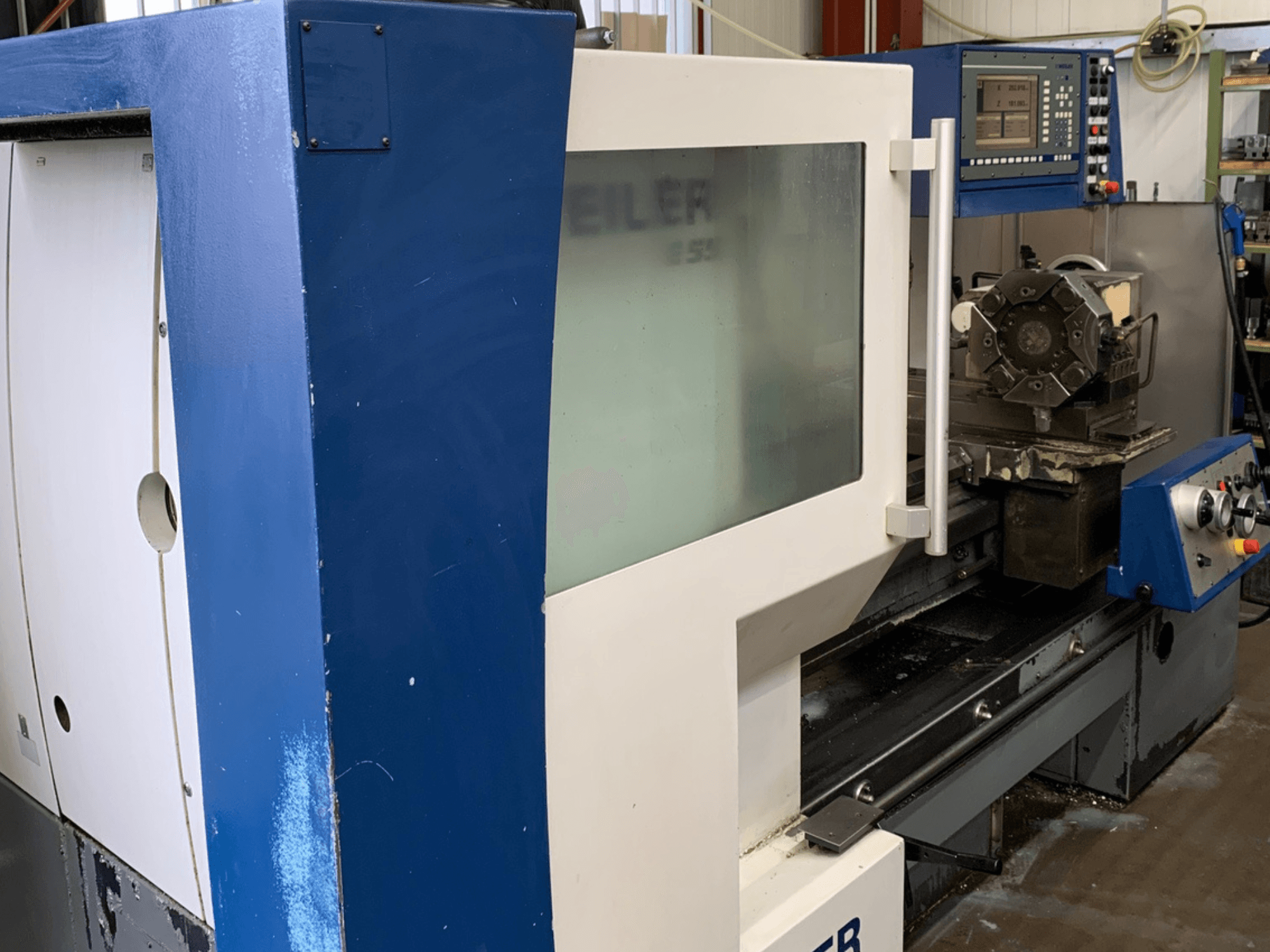 Máquina de torneamento horizontal Weiler E55X1000, vista lateral mostrando o painel de controlo e a configuração da ferramenta de corte.