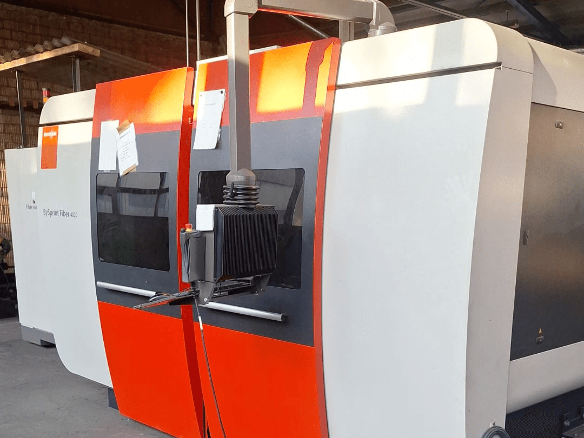 Máquina de corte a laser BySprint Fiber 4020, vista lateral, com um exterior vermelho e branco, painel de controlo detalhado visível.