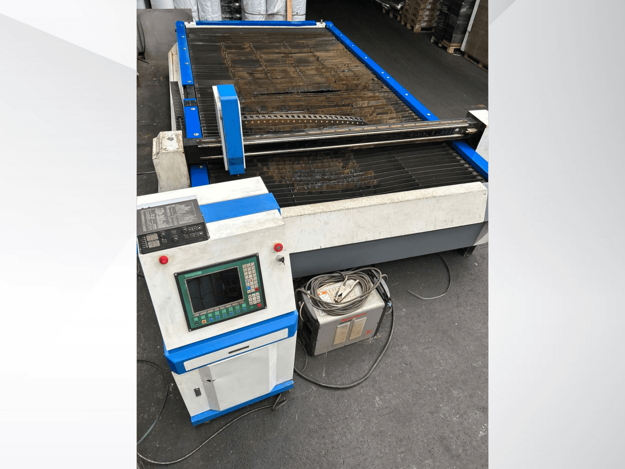Máquina de corte por plasma CNC com painel de controlo, vista frontal, com detalhes em azul e cabos no chão.