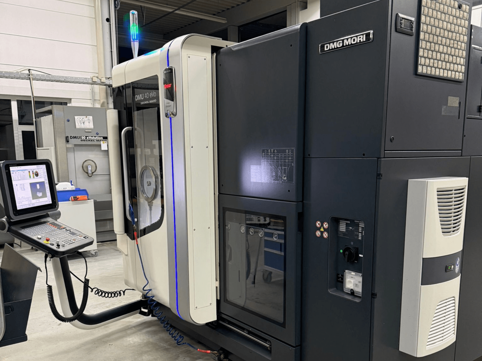 Máquina DMG MORI DMU 40 eVo, vista frontal mostrando os controlos, indicadores LED e design elegante que realça as caraterísticas industriais.