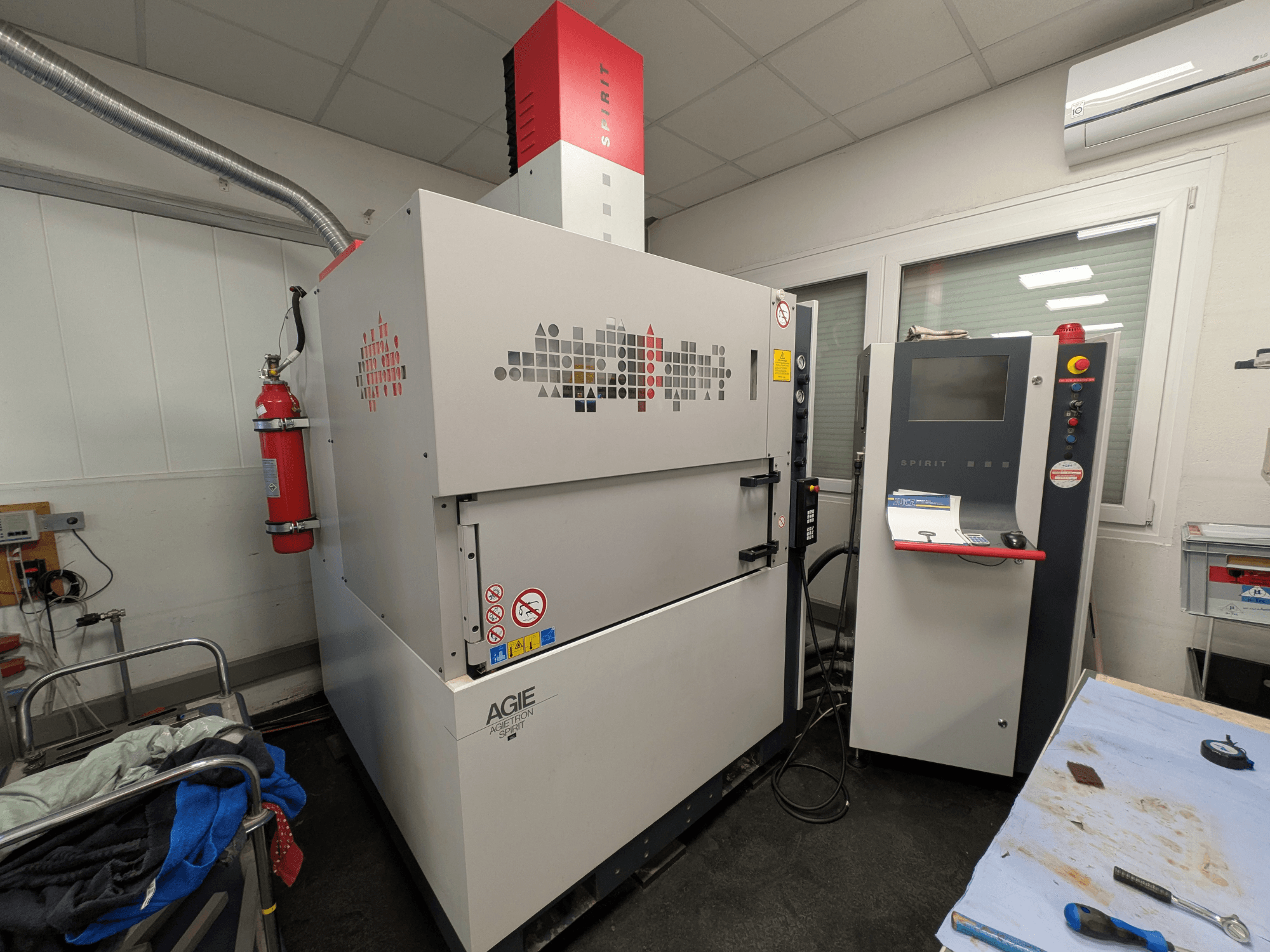 Máquina de electroerosão por penetração AGIE AGIETRON SPIRIT 3, vista lateral, mostrando o painel de controlo e o extintor de incêndio.