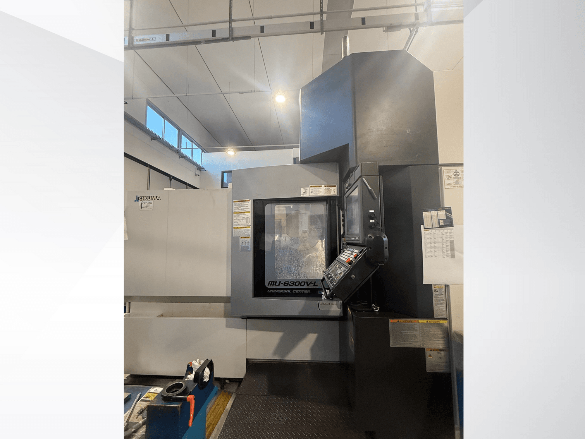 Máquina CNC Okuma MU-6300V-L vista de frente, mostrando o painel de controlo e as etiquetas de segurança.
