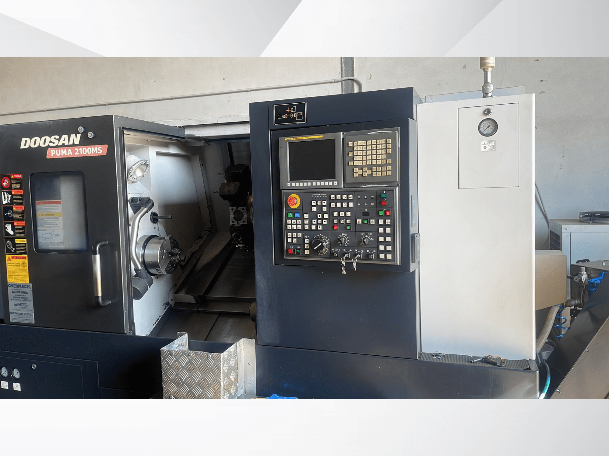 Vista frontal da máquina de torneamento horizontal DOOSAN PUMA 2100MS, mostrando o painel de controlo, o fuso e as ferramentas de corte no interior da câmara.