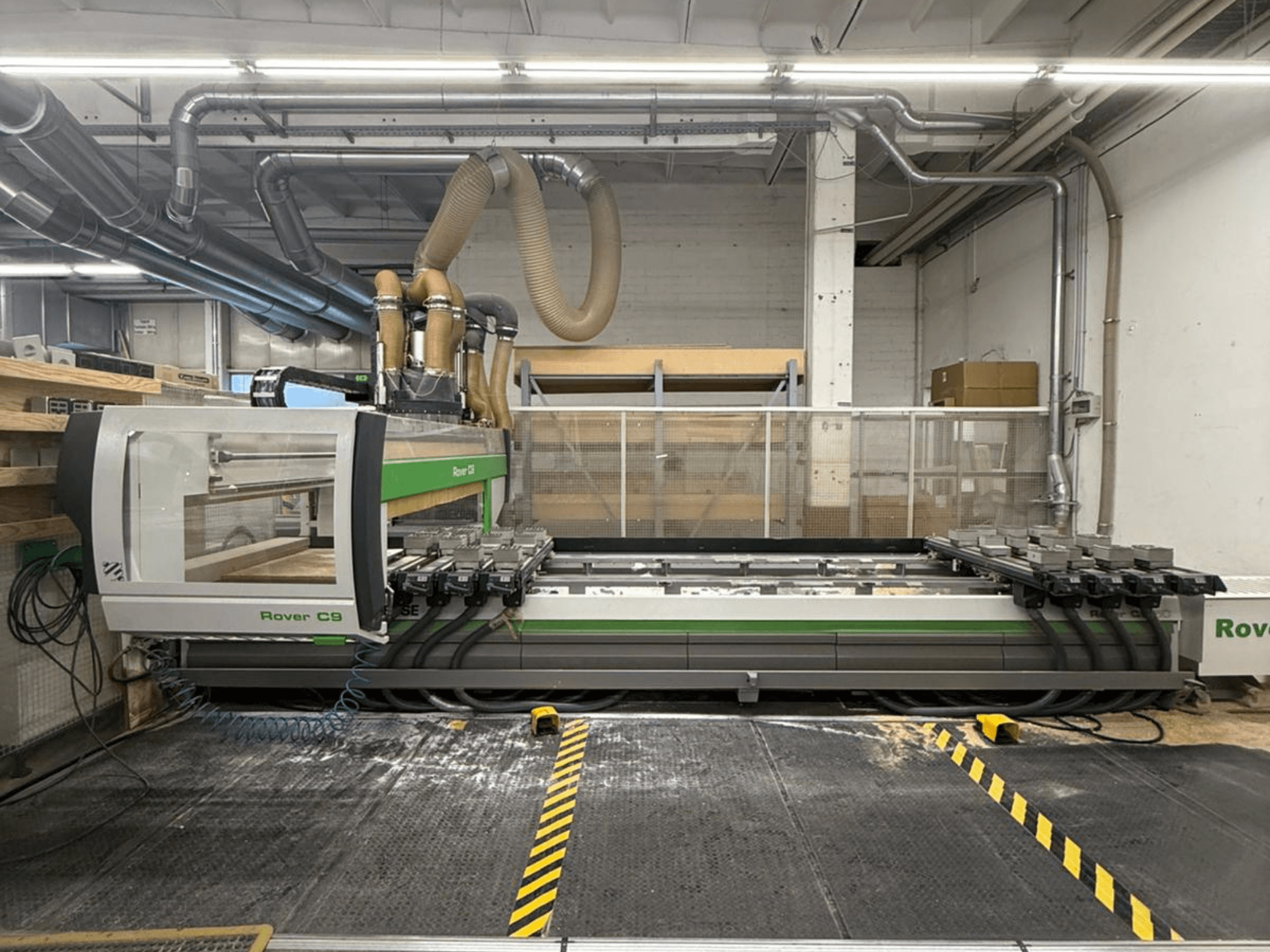 Máquina CNC Rover C9 numa oficina, vista frontal, com várias cabeças de corte e sistema de extração de poeiras visível.
