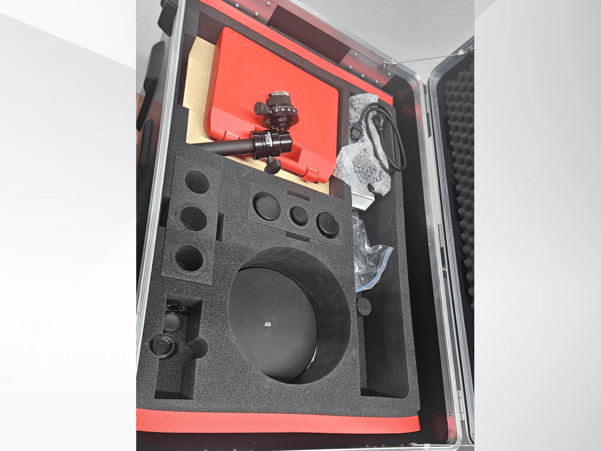 Componentes da máquina de medição ótica ZEISS GOM ATOS 5 numa caixa forrada a espuma, com uma objetiva, acessórios e embalagem de proteção.