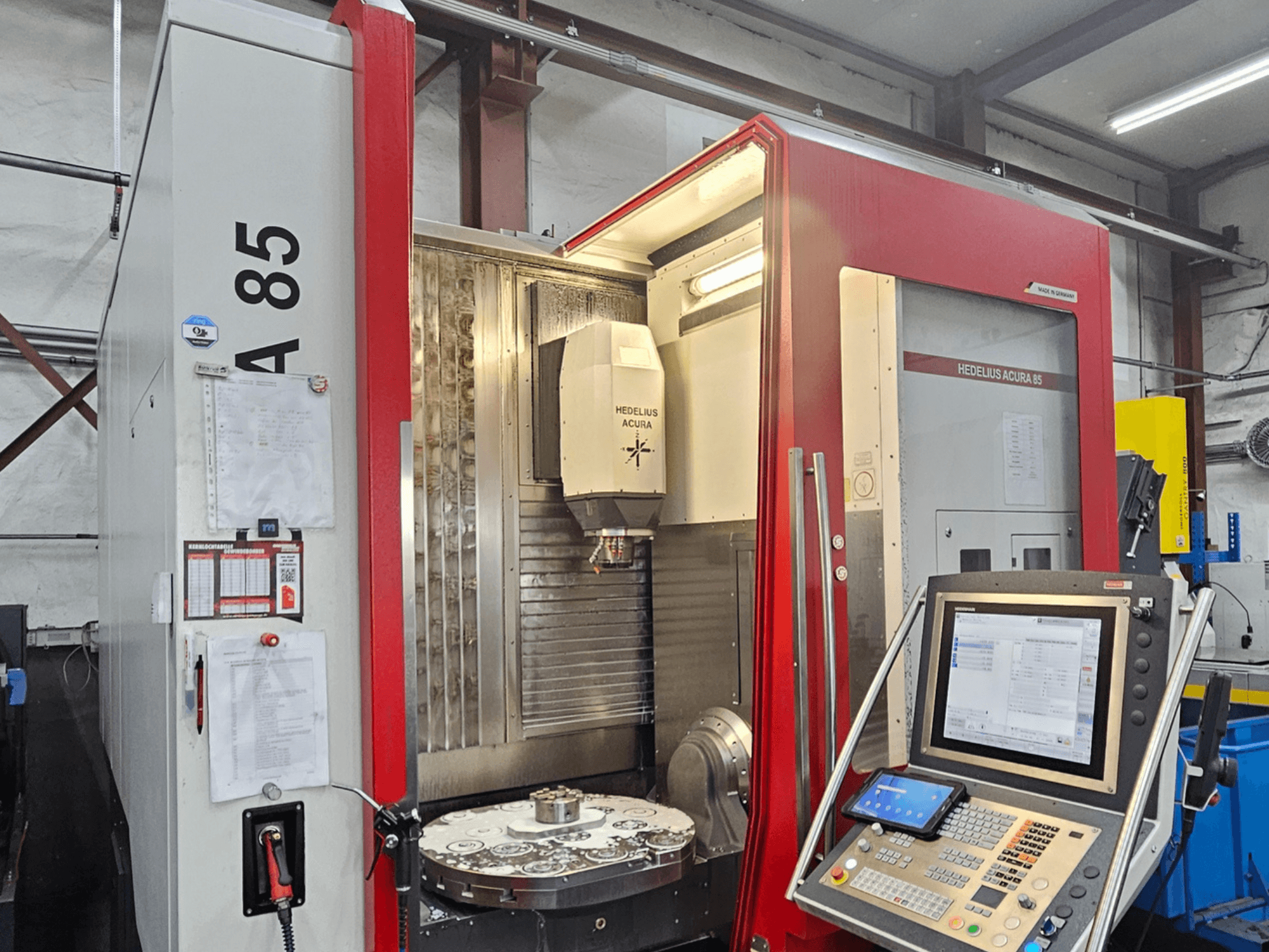 Centro de maquinação vertical HEDLIUS Acura 85, vista frontal, com painel de controlo e uma mesa rotativa para maquinação de precisão.