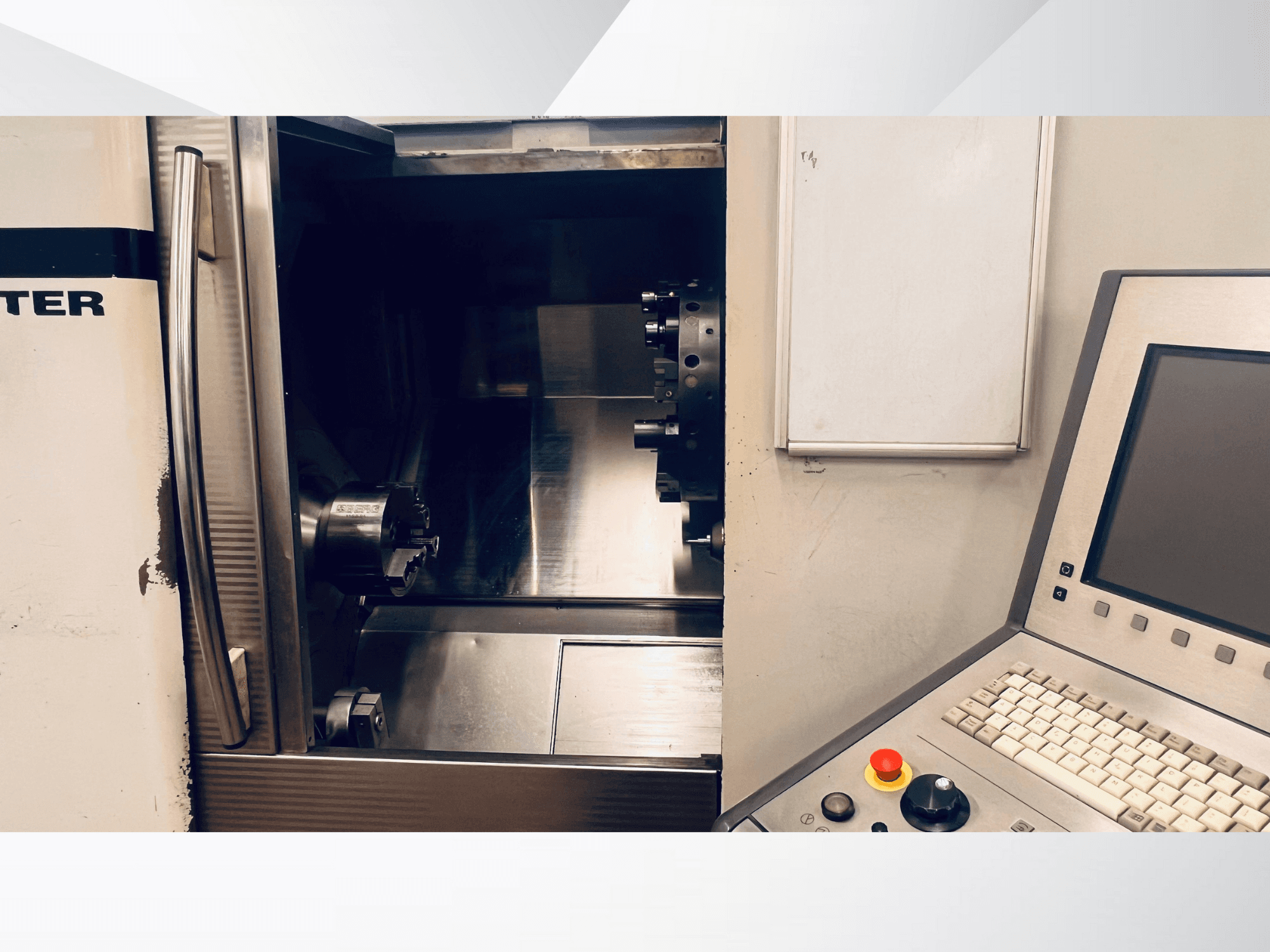 Vista frontal de uma máquina CNC mostrando a câmara aberta e o painel de controlo com um teclado e um botão de paragem de emergência.