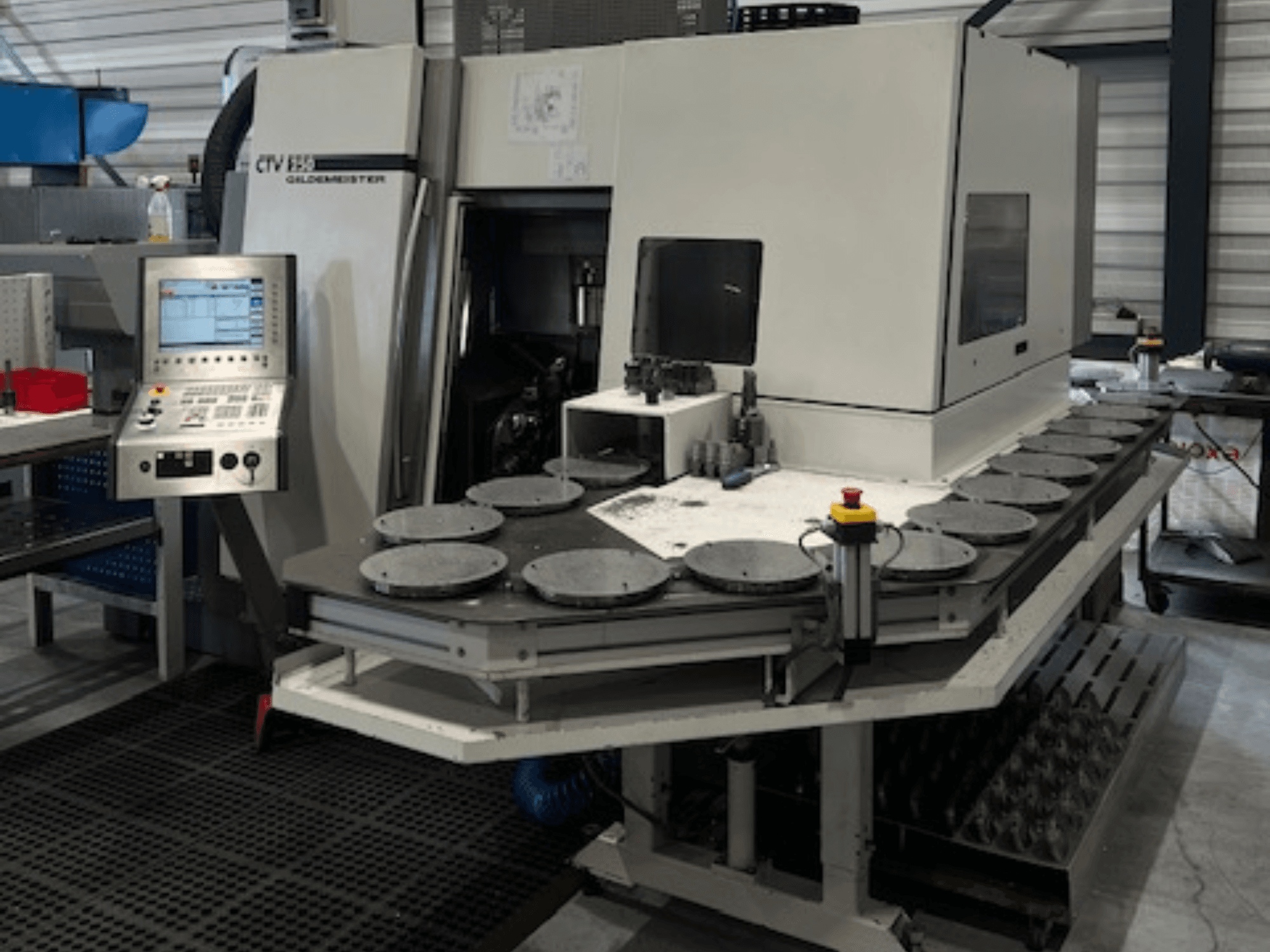 Texto alternativo: Unidade de maquinagem CTV E33 Goldmeister numa oficina, vista frontal, com painel de controlo e múltiplas plataformas de trabalho circulares.