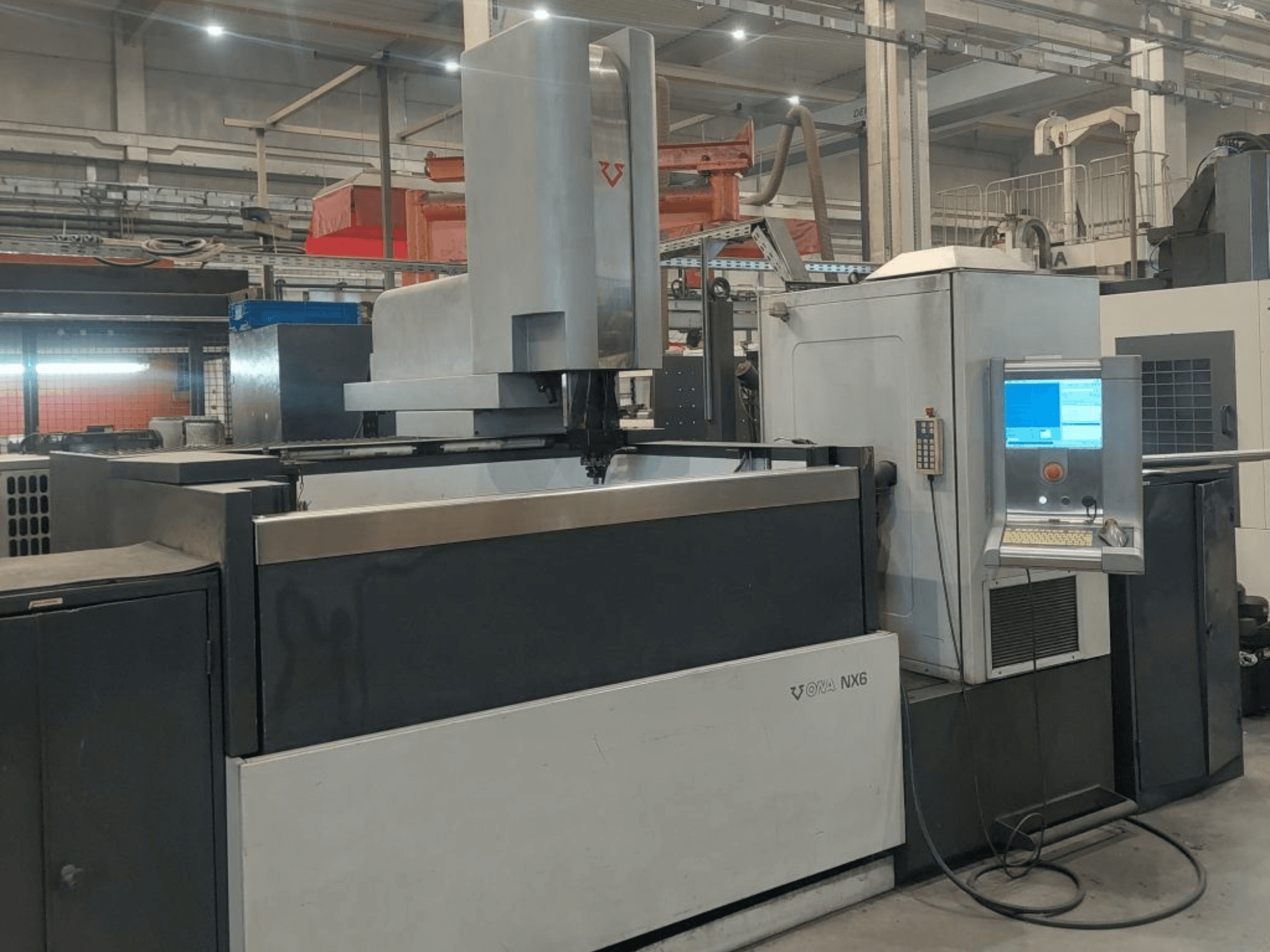 Máquina de eletroerosão por penetração ONA NX6, vista de frente, com um painel de controlo e uma ampla área de trabalho para usinagem de precisão.