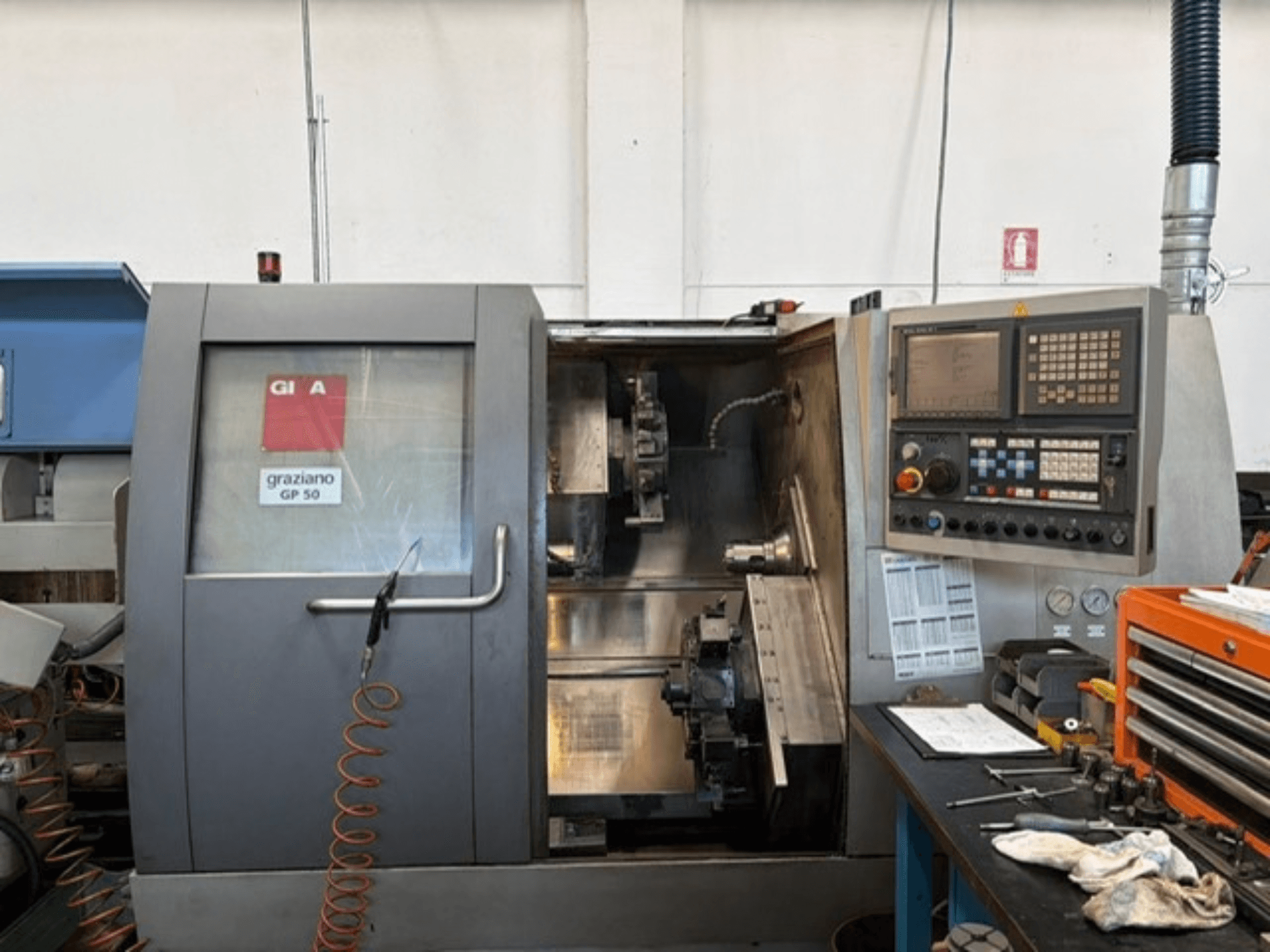 Torno horizontal Gildemeister GP 50, vista frontal, mostrando o painel de controlo e a área de trabalho aberta com ferramentas.