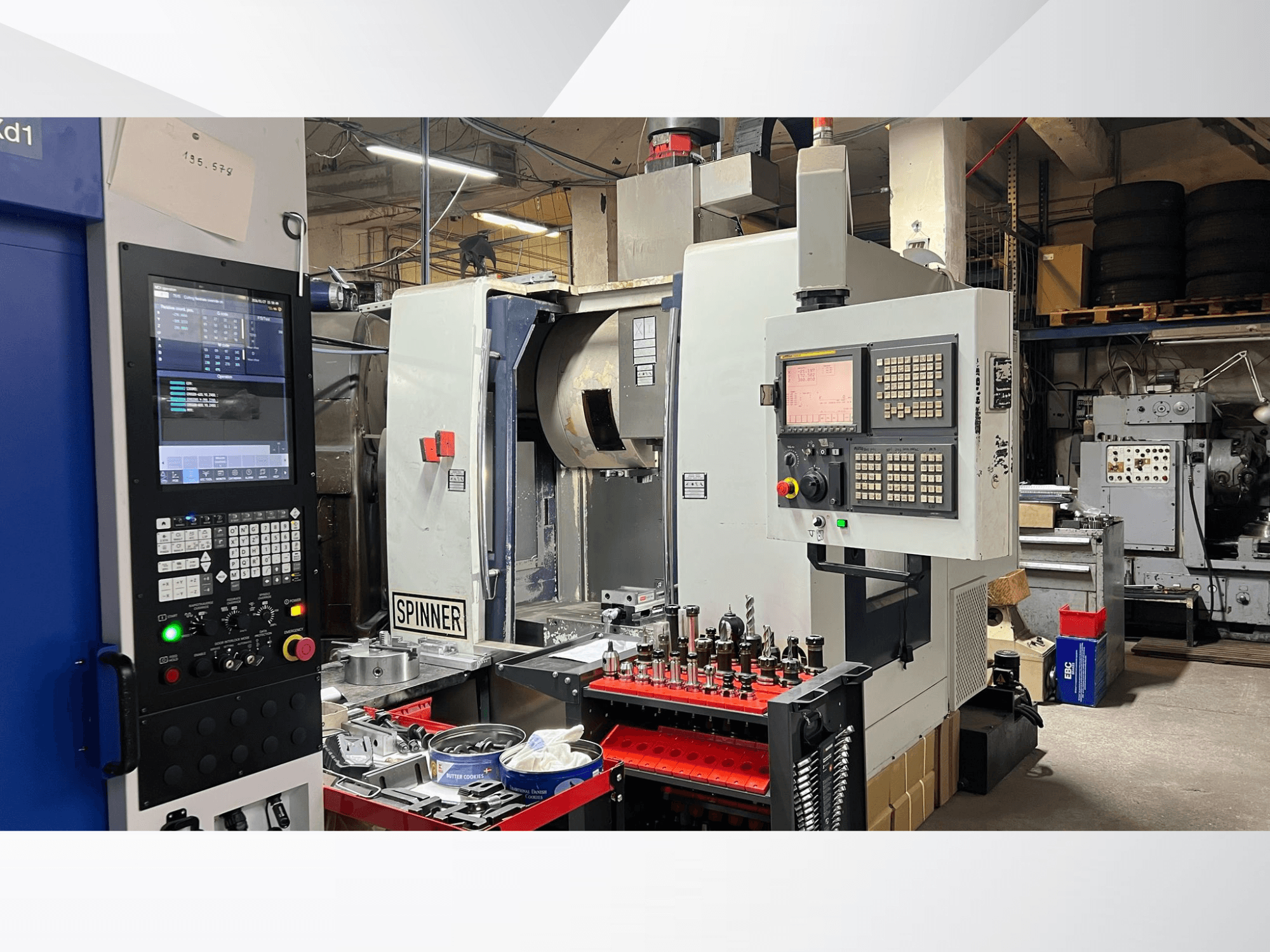 Máquina CNC com painel de controlo, ferramentas e peças de trabalho visíveis, vista de um ângulo frontal num ambiente de oficina.