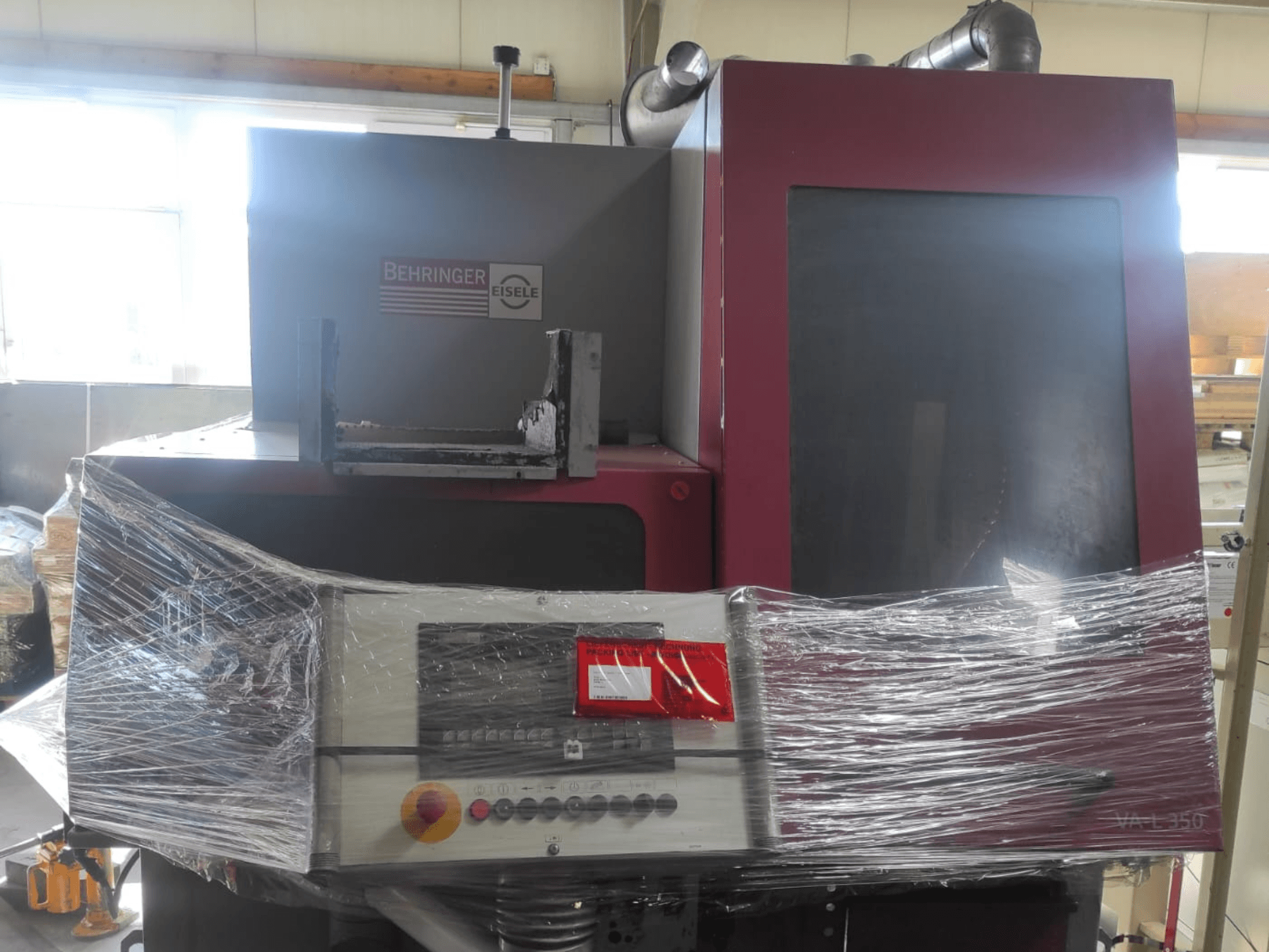 Máquina Behringer Eisele VA L 560, vista frontal, embrulhada em plástico, com painel de controlo e botões visíveis.