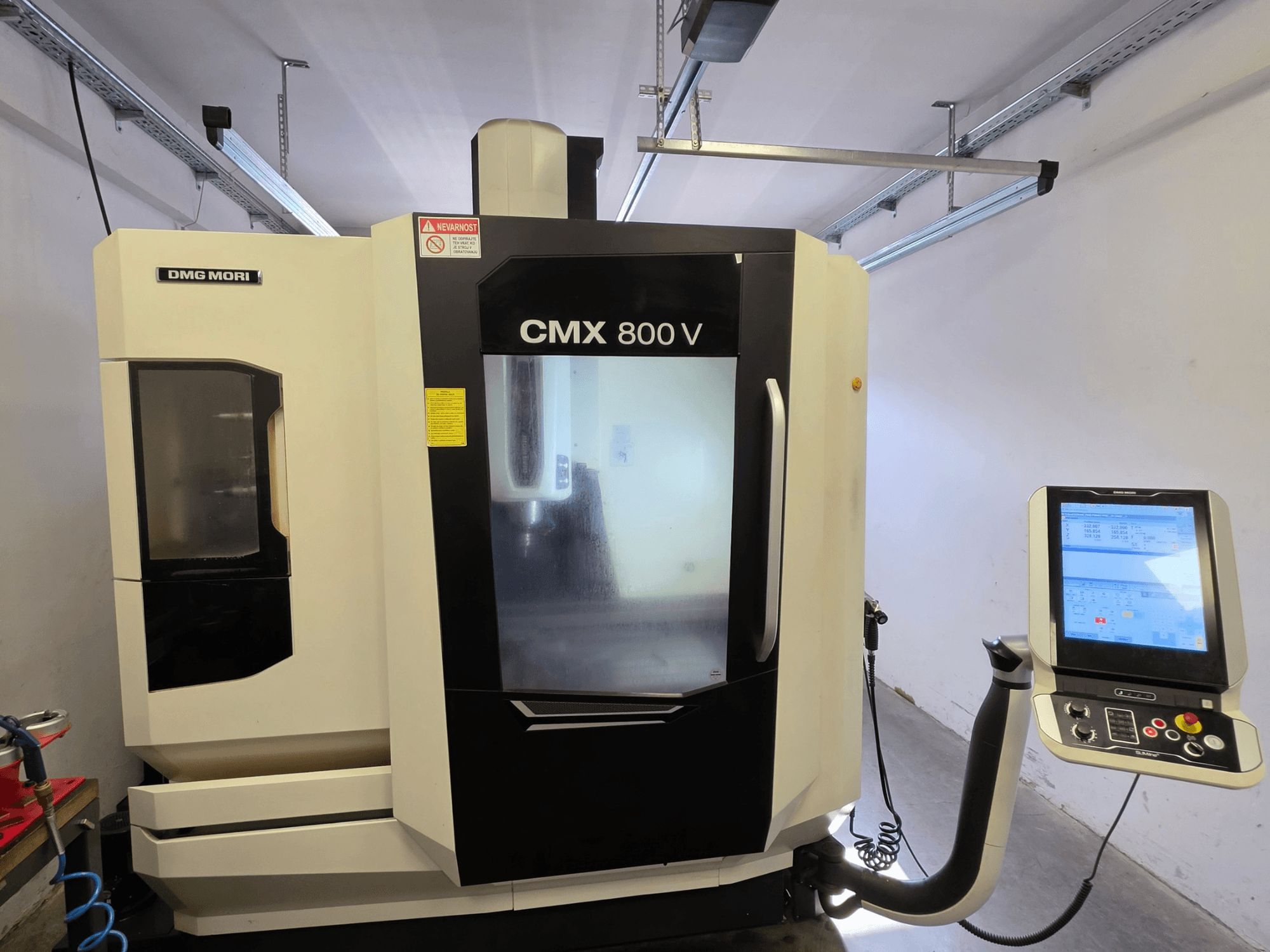 Centro de maquinagem vertical DMG MORI CMX 800V, vista frontal, com um painel de controlo com ecrã tátil e sinalização de segurança clara.
