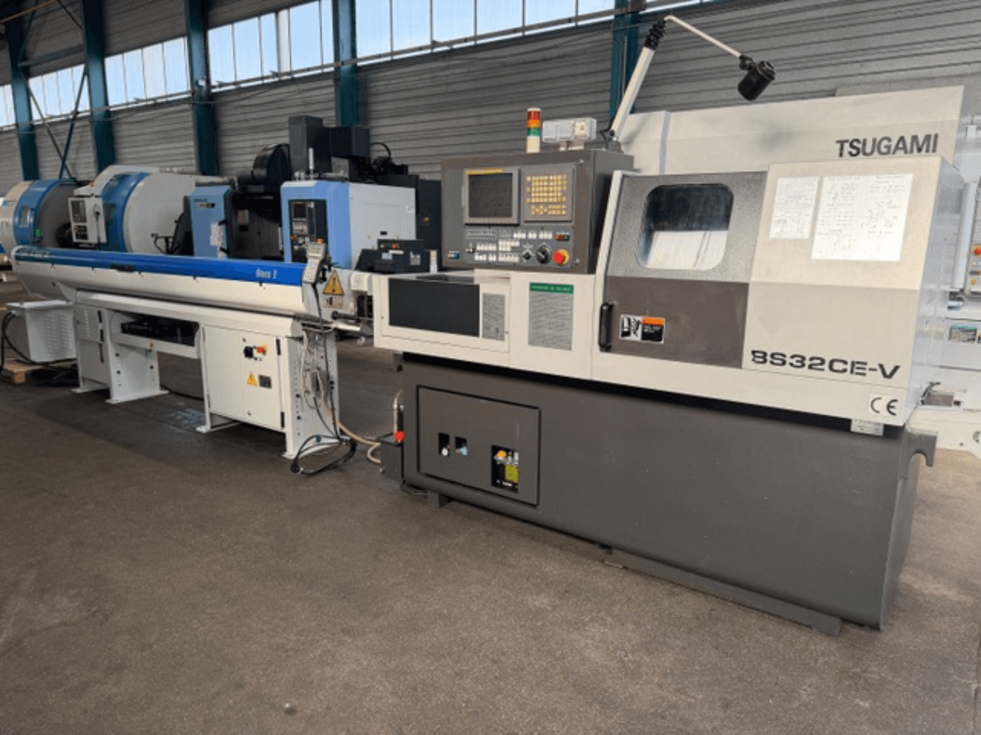 Vista frontal de um torno TSUGAMI BS32CE-V de tipo suíço, com painel de controlo e fuso montado.