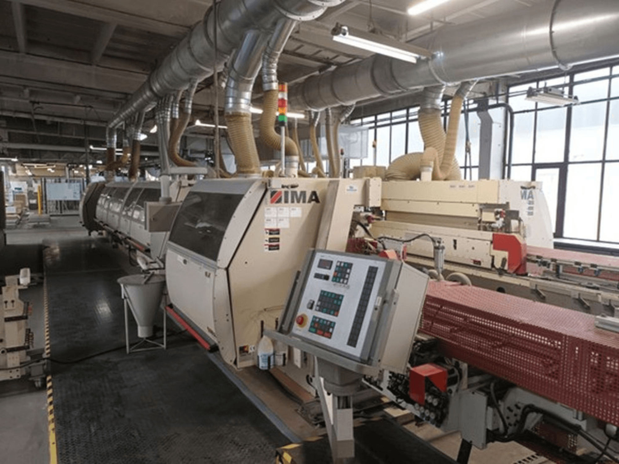 Máquinas industriais IMA em ambiente fabril, vista frontal, com painéis de controlo e tubos de extração de poeiras.