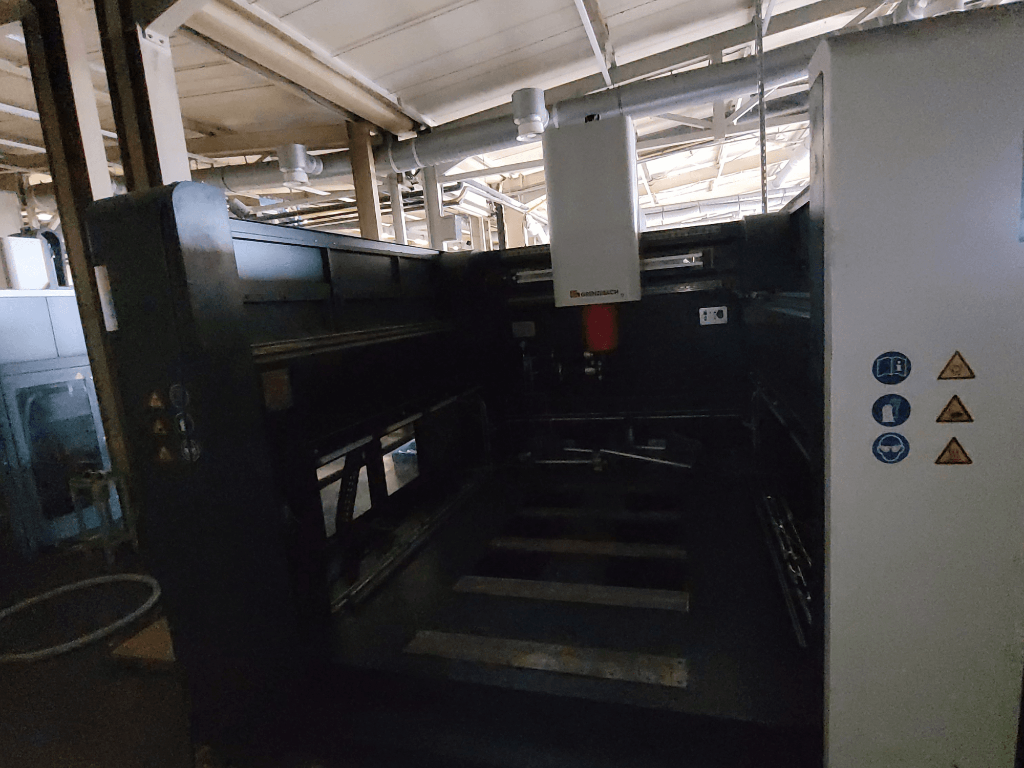 Máquina FSW DSM 3000 da GRENZEBACH, vista lateral que mostra os comandos, os símbolos de segurança e a área de trabalho para as tarefas de maquinagem.