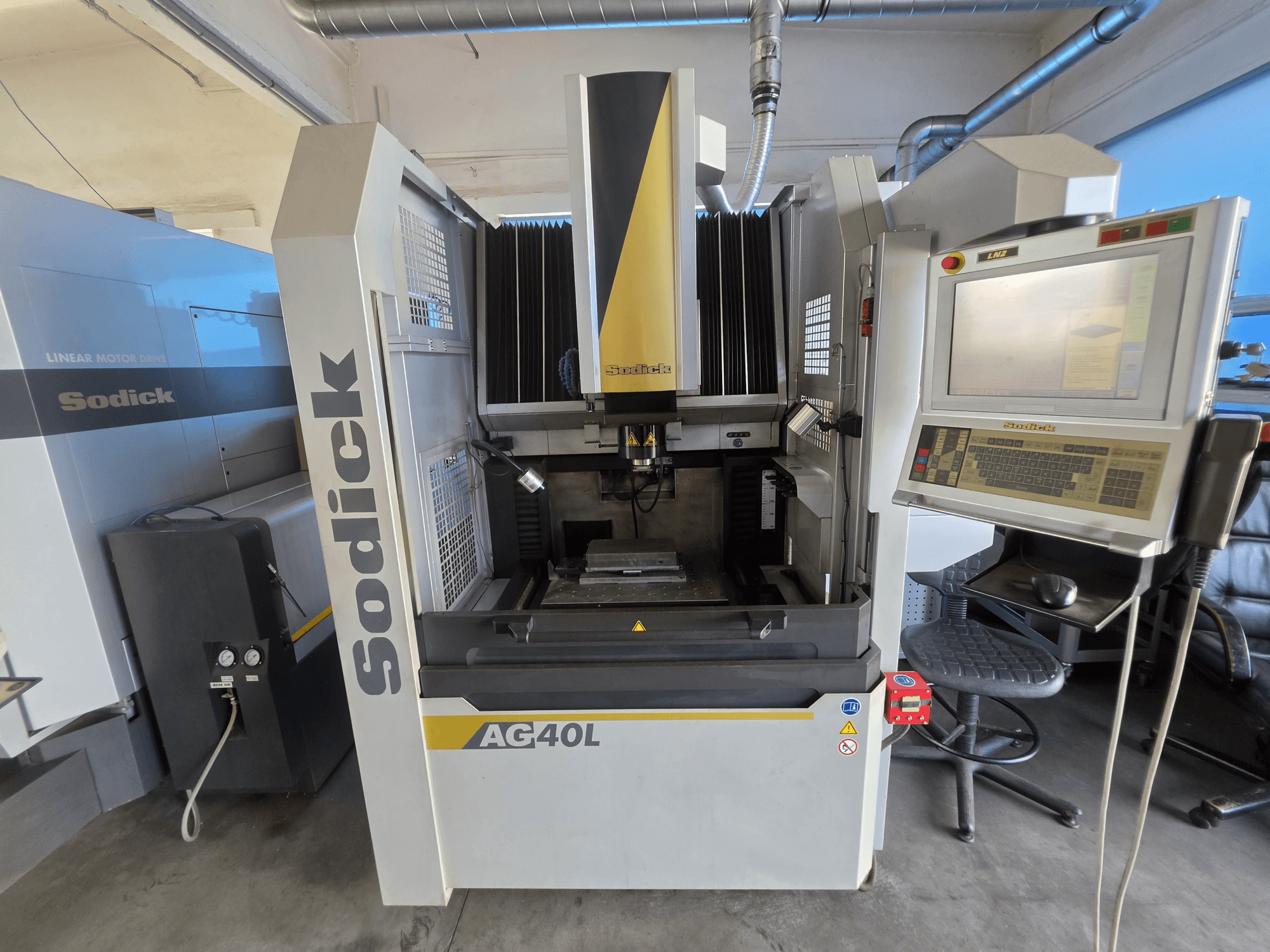 Máquina de eletroerosão por penetração Sodick AG40L LN2, vista frontal com o painel de controlo, o sistema de acionamento por motor linear e o suporte da peça de trabalho visíveis.