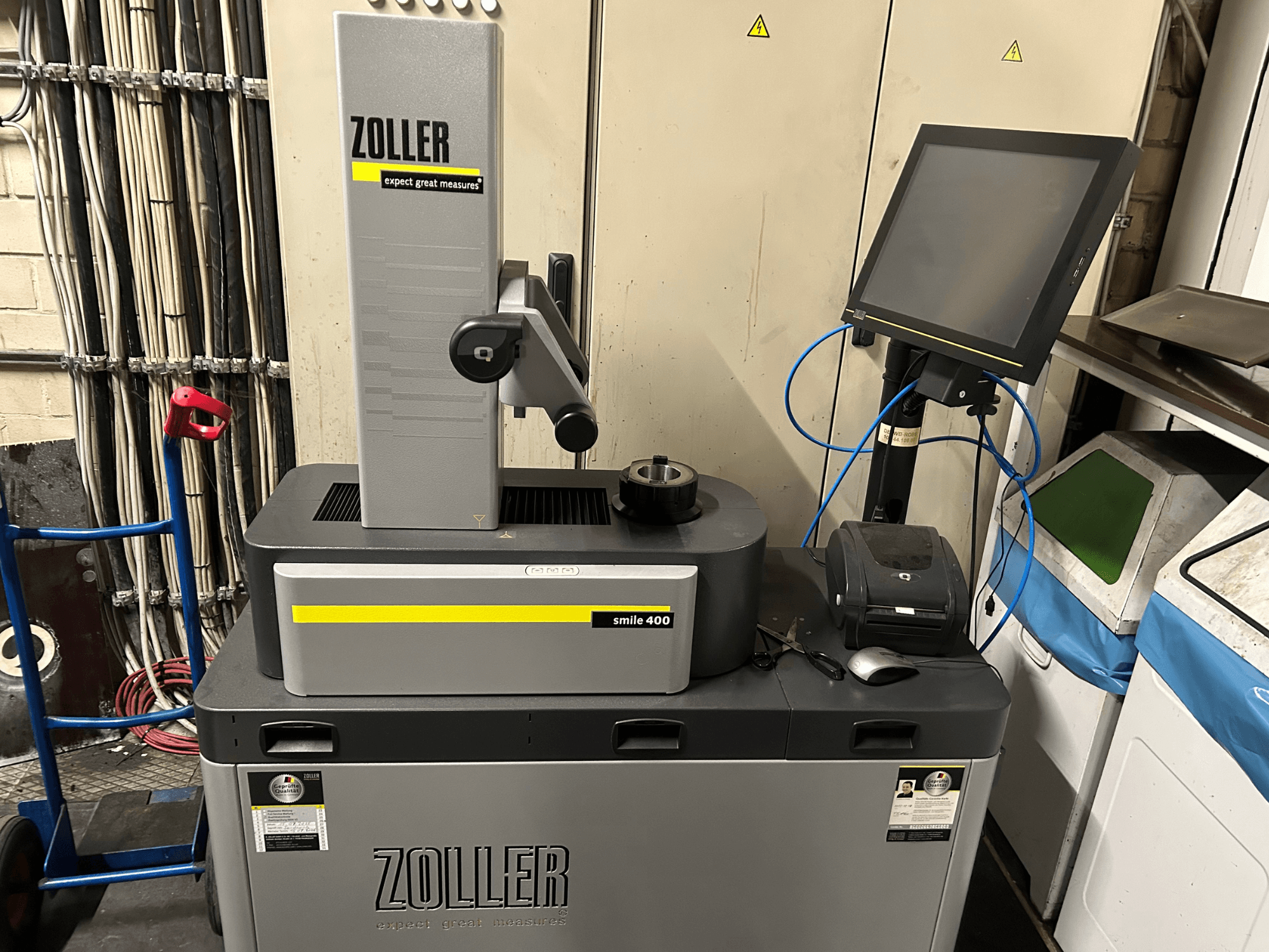 Máquina de medição ZOLLER smile 400 em cinzento, vista frontal, com ecrã tátil, suporte de ferramentas e impressora numa superfície de trabalho.