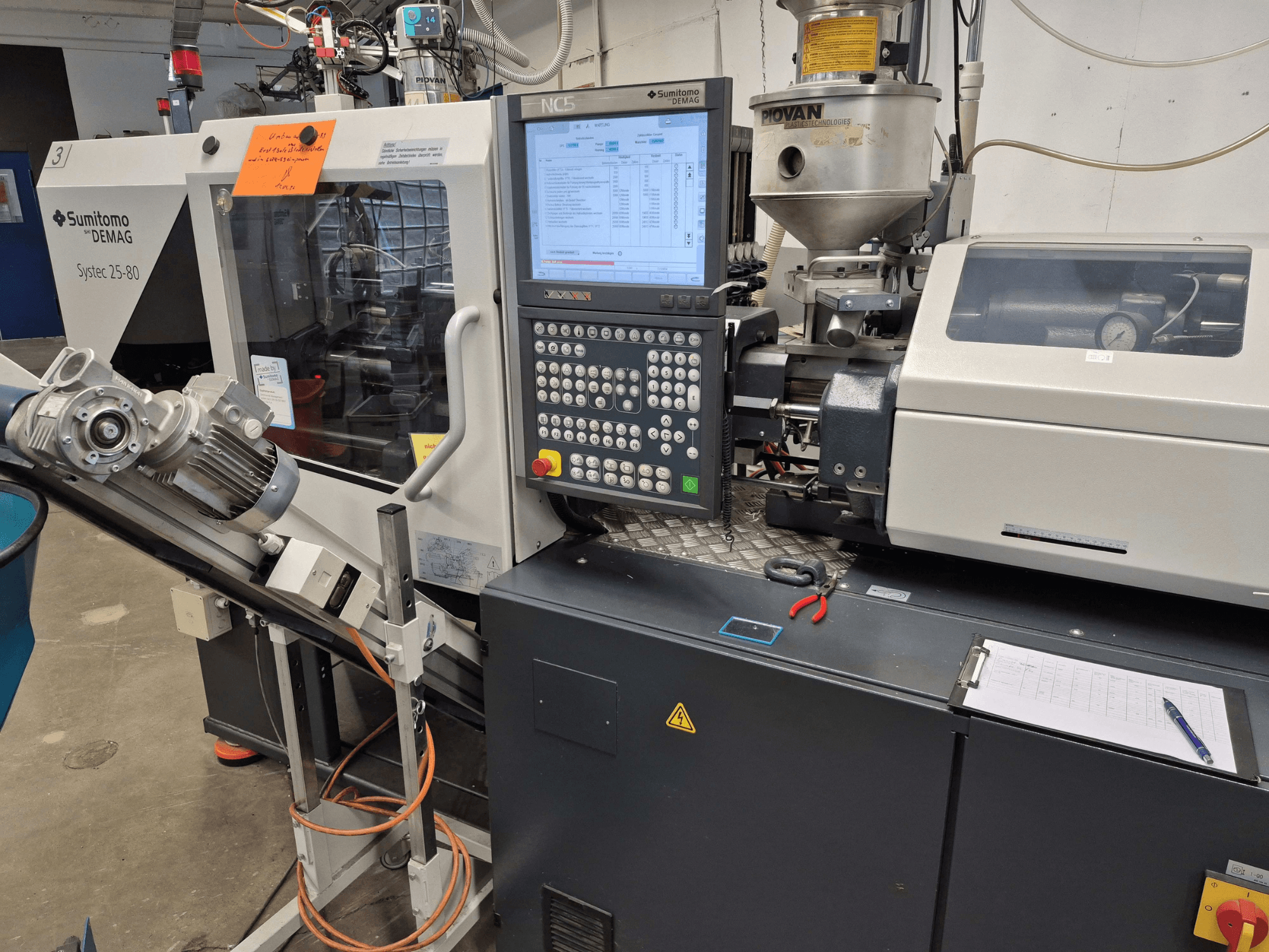 Máquina de moldagem por injeção hidráulica SUMITOMO SHI DEMAG Systec 25/320-80, vista frontal com o painel de controlo e o sistema de alimentação visíveis.