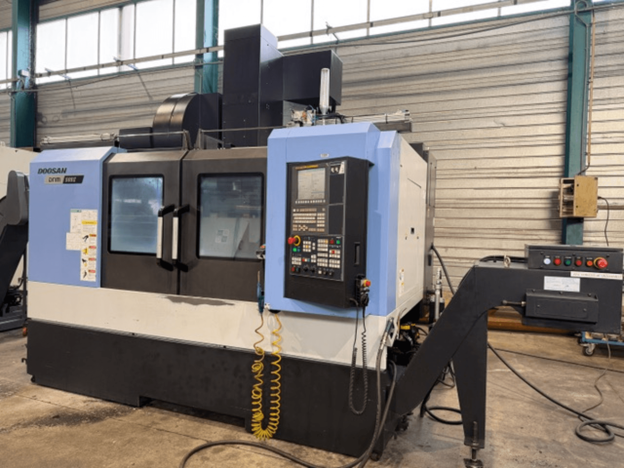 Fresadora CNC Doosan DNM 500II em vista frontal, com painel de controlo e porta-ferramentas, numa configuração de fábrica.