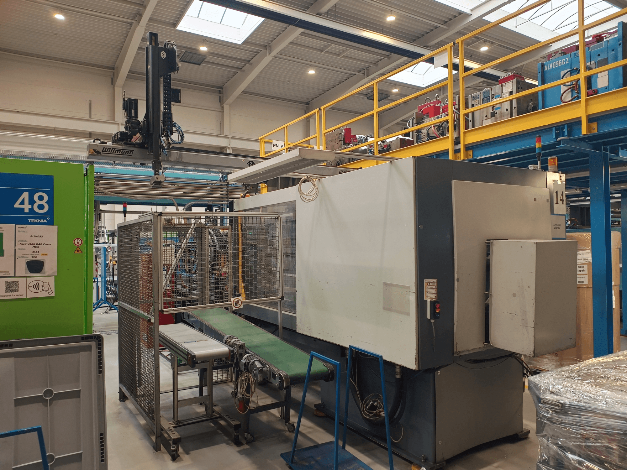 Máquina de automação industrial da Winmon, vista lateral mostrando o tapete transportador, o painel de controlo e a gaiola de segurança numa fábrica.