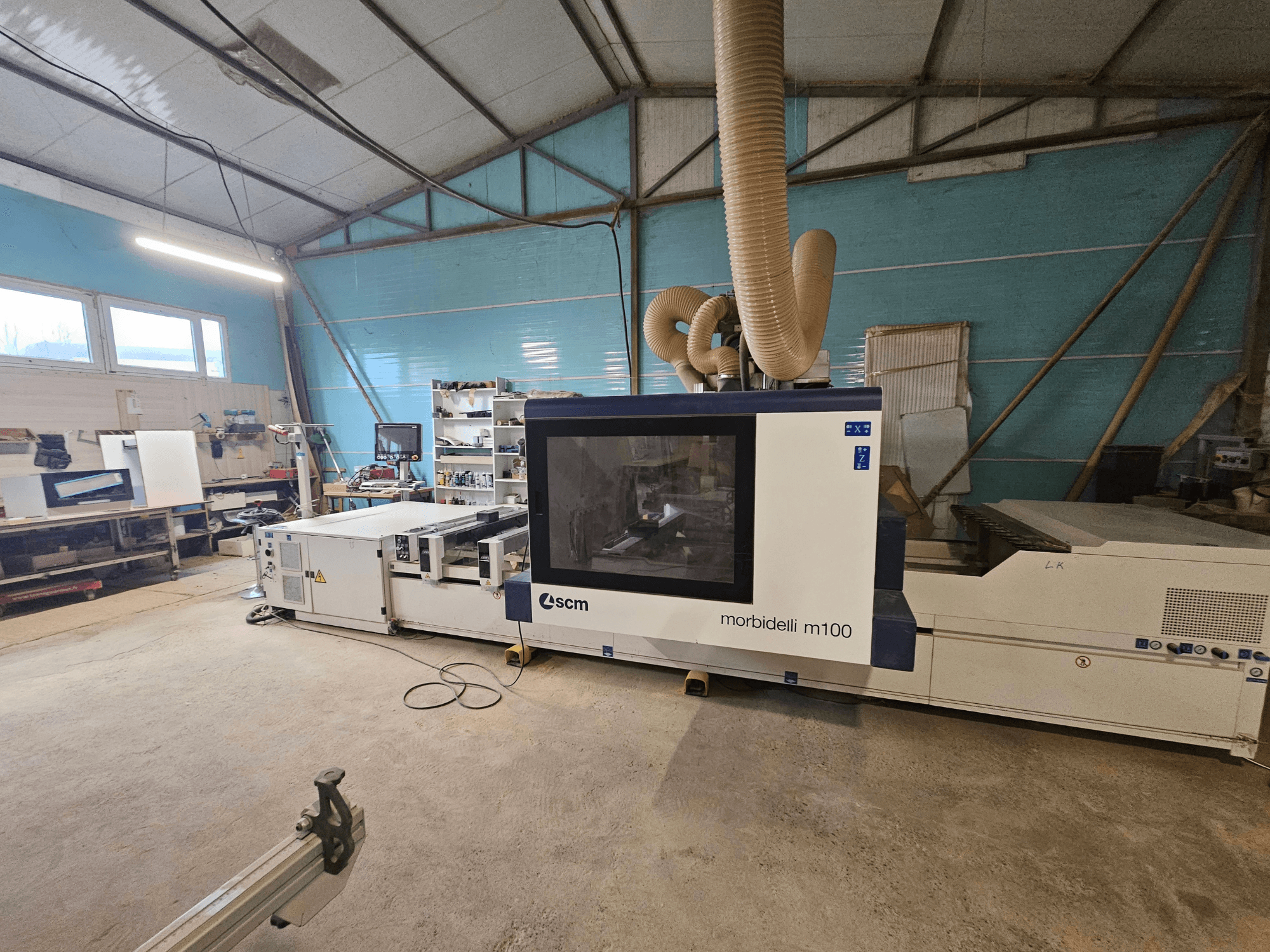 Máquina CNC SCM Morbidelli M100 numa oficina, vista frontal, mostrando o sistema de extração de poeiras e o painel de controlo.