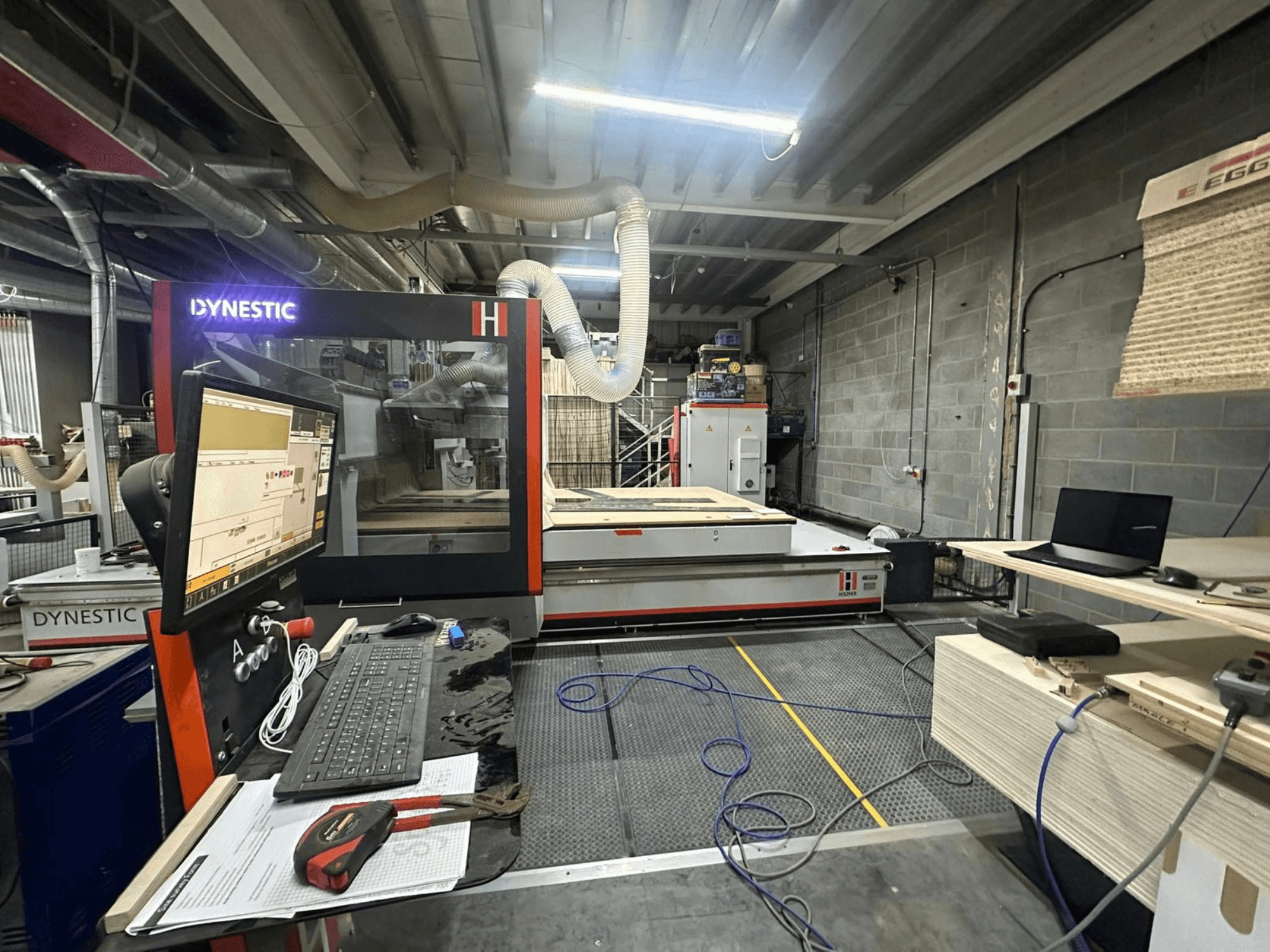 Fresadora de madeira HOLZHER Dynestic 7535 em oficina, mostrando painel de controlo, monitor e materiais na mesa de trabalho, vista frontal.