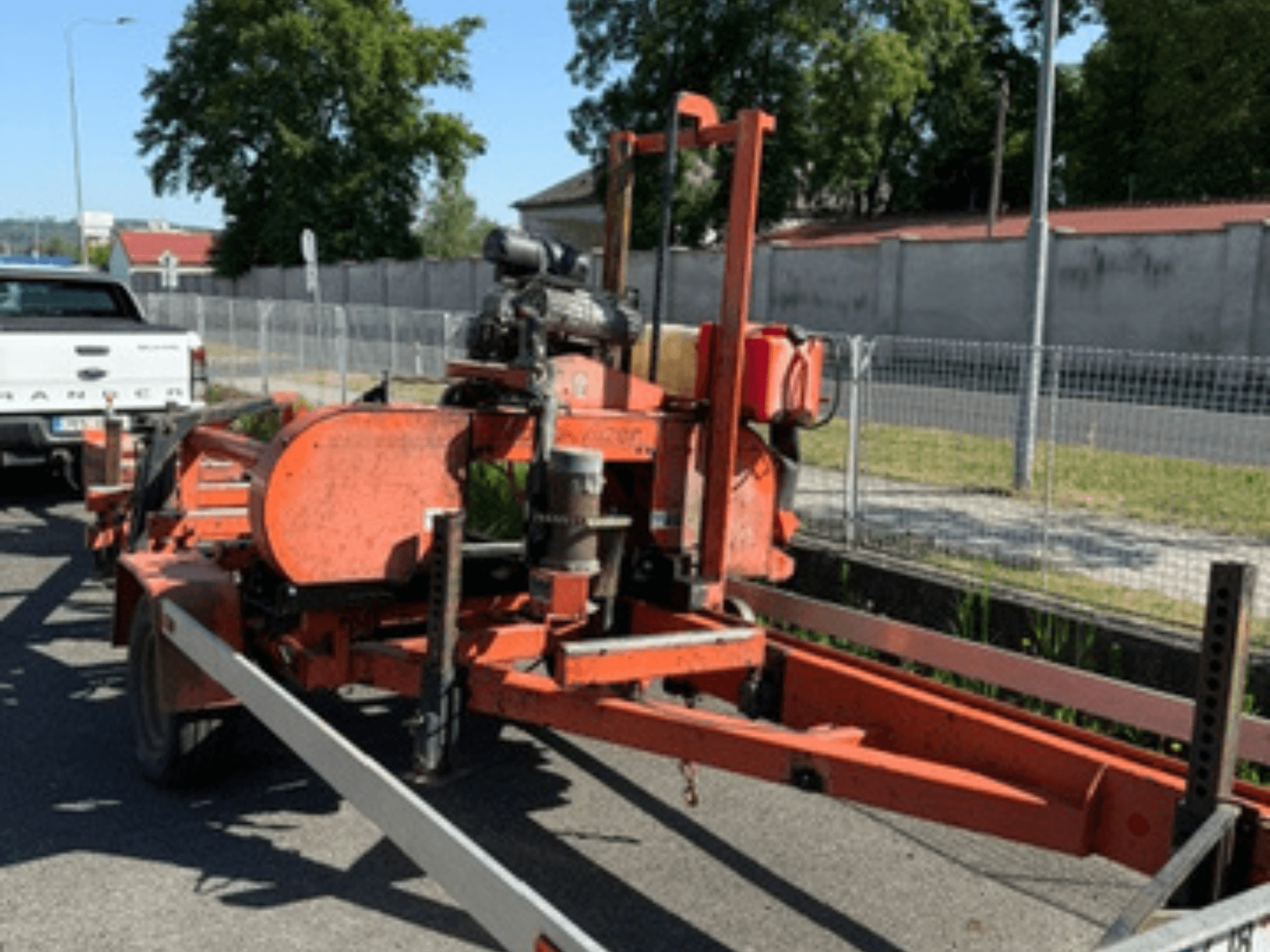 Serra de fita para madeira WOOD-MIZER LT40 na cor laranja, vista lateral num reboque com rodas e componentes do motor visíveis.