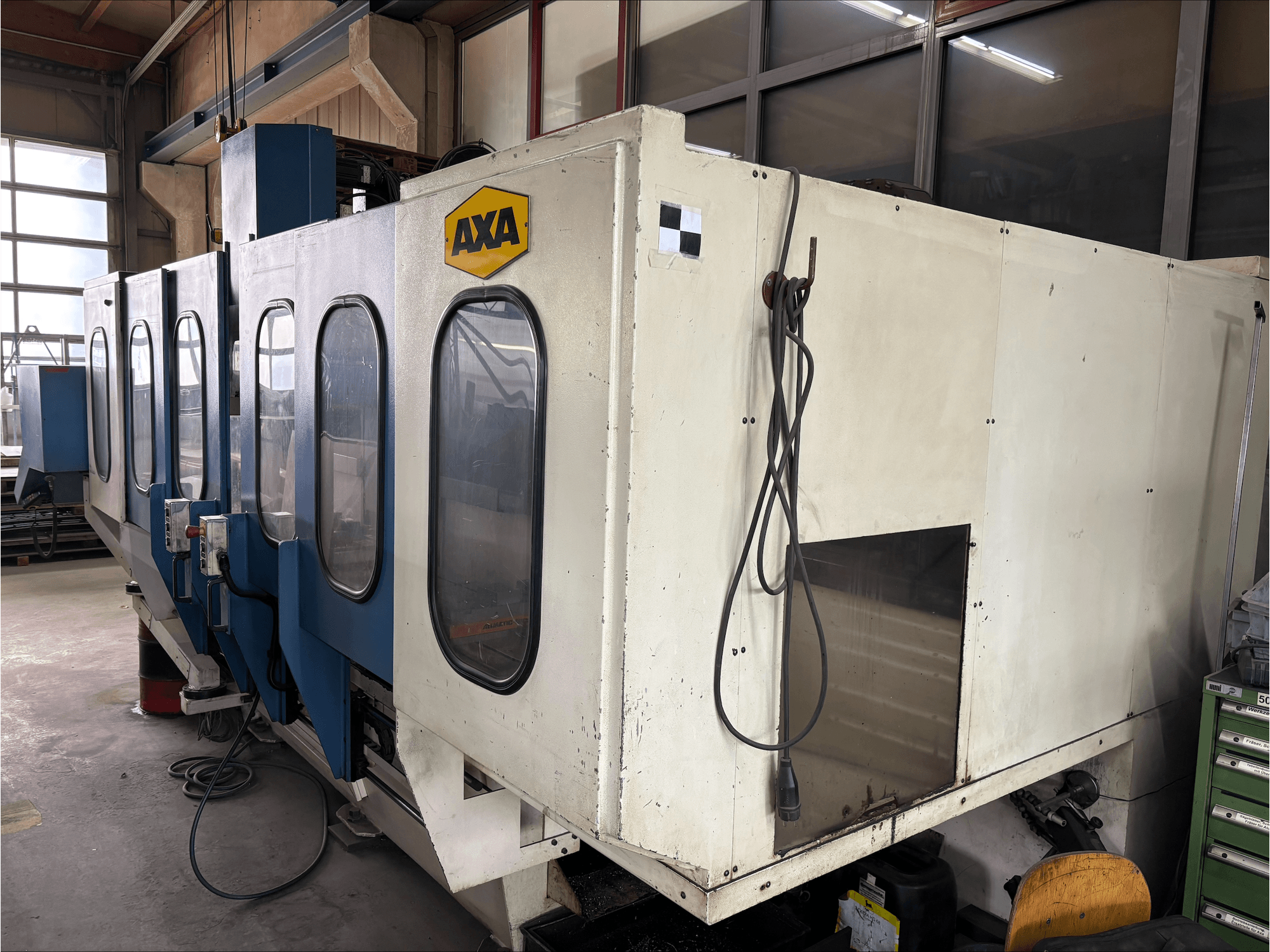 Centro de maquinação vertical AXA VSC-1-M/C, vista frontal, com um grande armário branco e painel de controlo azul.