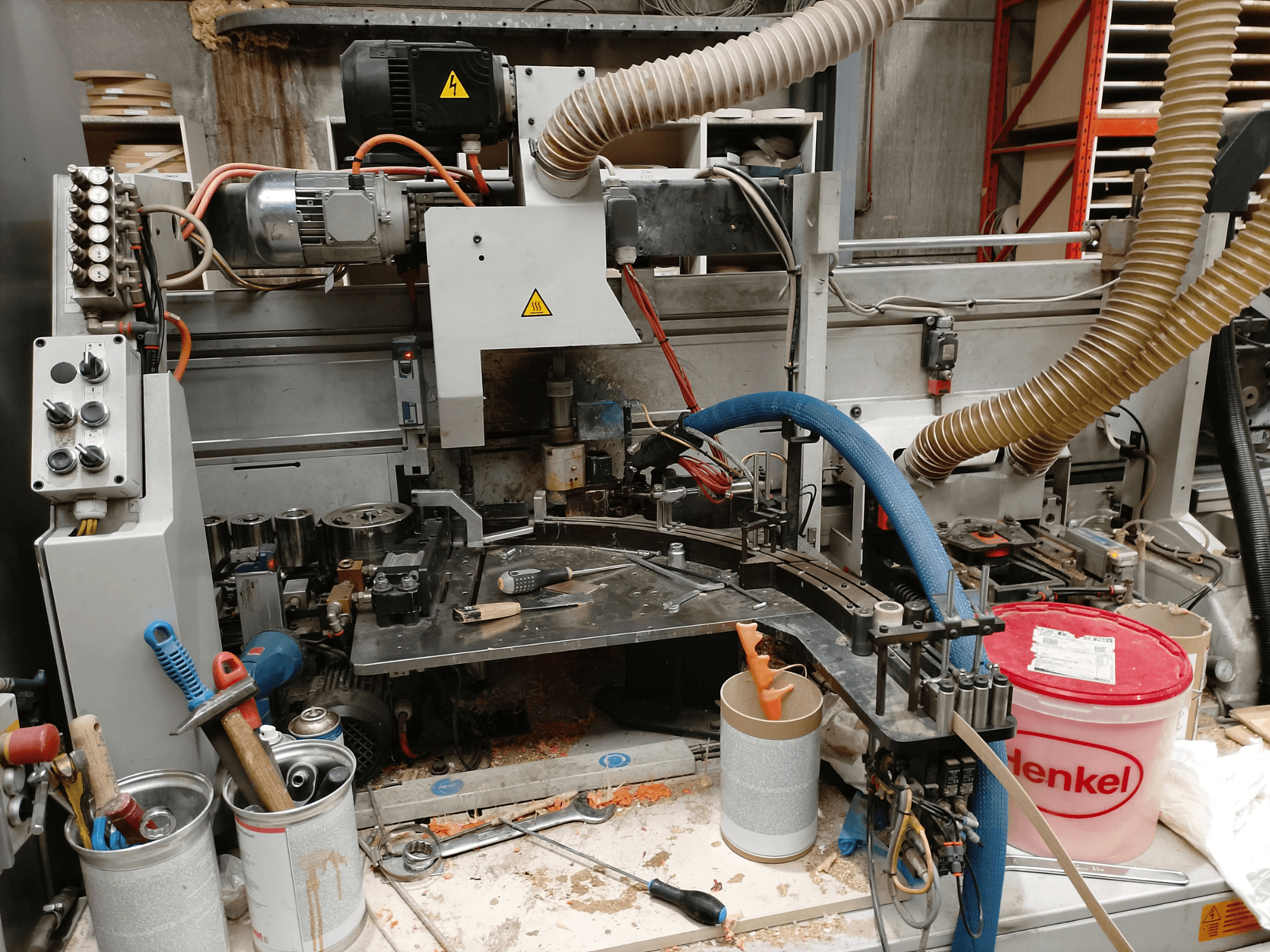 BIESSE Edge Stram B1 em vista frontal, mostrando máquinas, mangueiras e ferramentas de trabalho entre aparas de madeira.