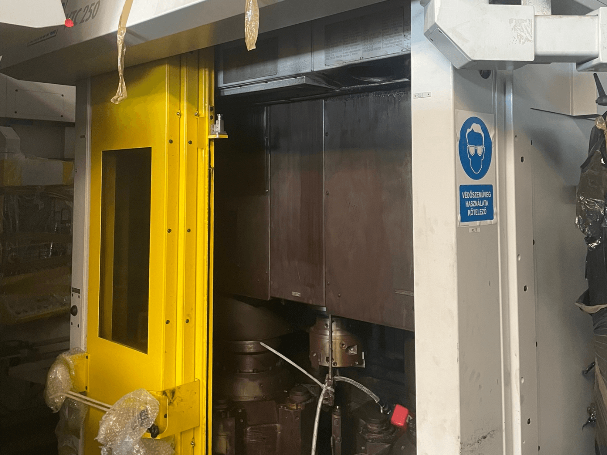 Porta de entrada amarela de uma máquina com sinal de segurança, vista frontal de uma máquina industrial modelo Z250, mostrando os componentes internos.