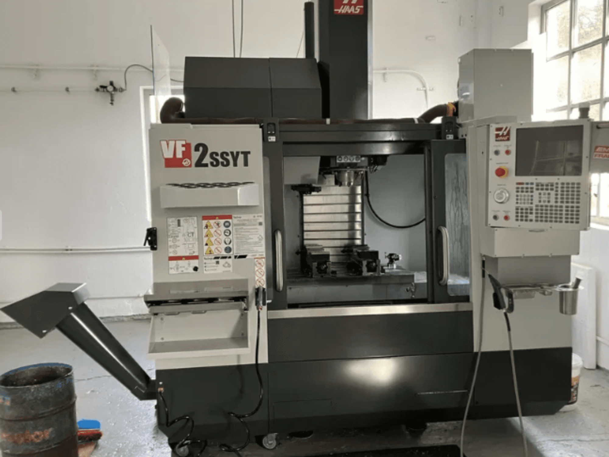 Fresadora CNC Haas VF-2SSYT, vista frontal, apresenta painel de controlo, suporte de ferramentas e sistema de refrigeração para maquinagem de metais.