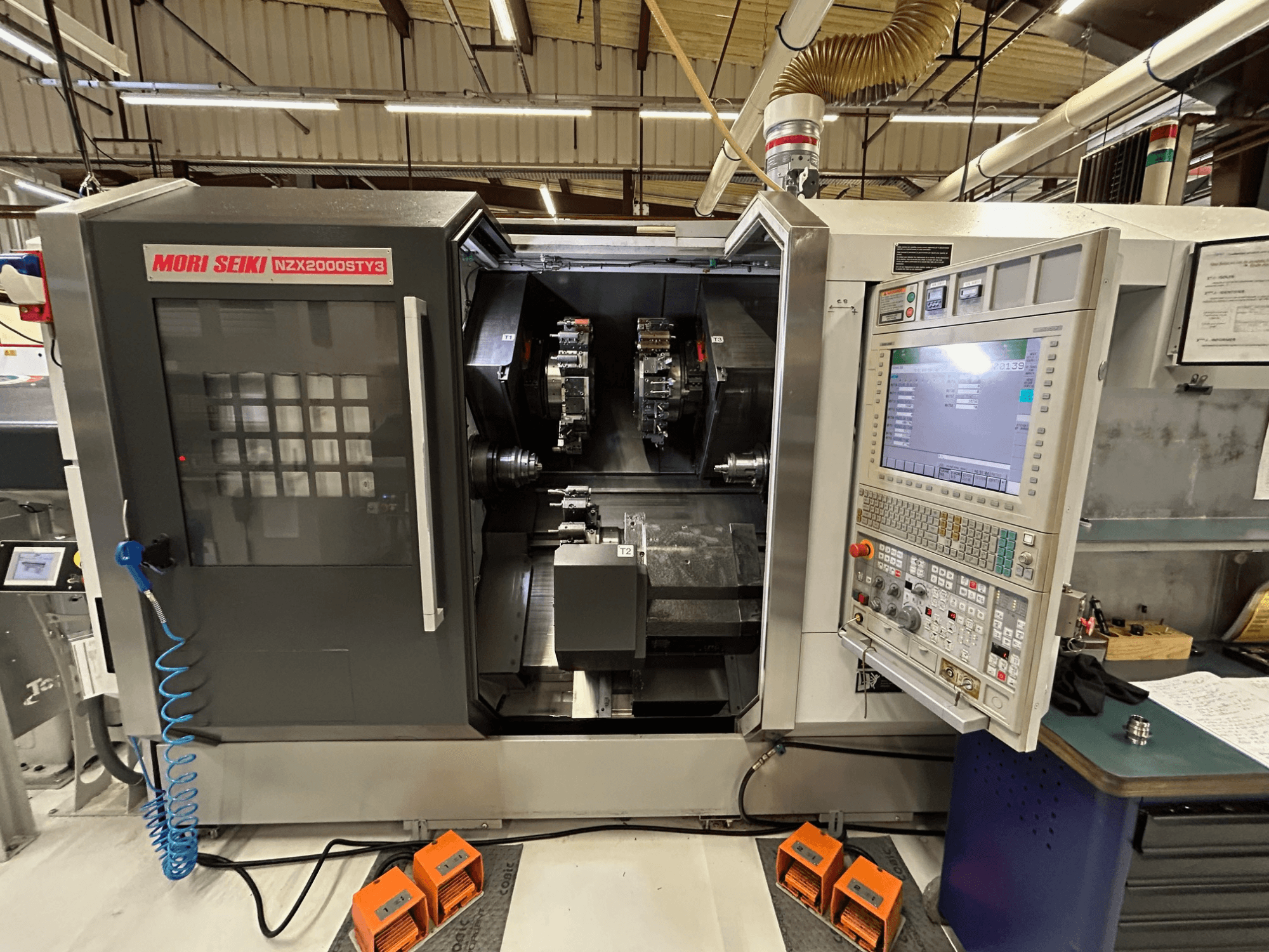 Torno multifuso MORI SEIKI NZ2000 ST3Y3, vista frontal que mostra o painel de controlo e a área de maquinagem.