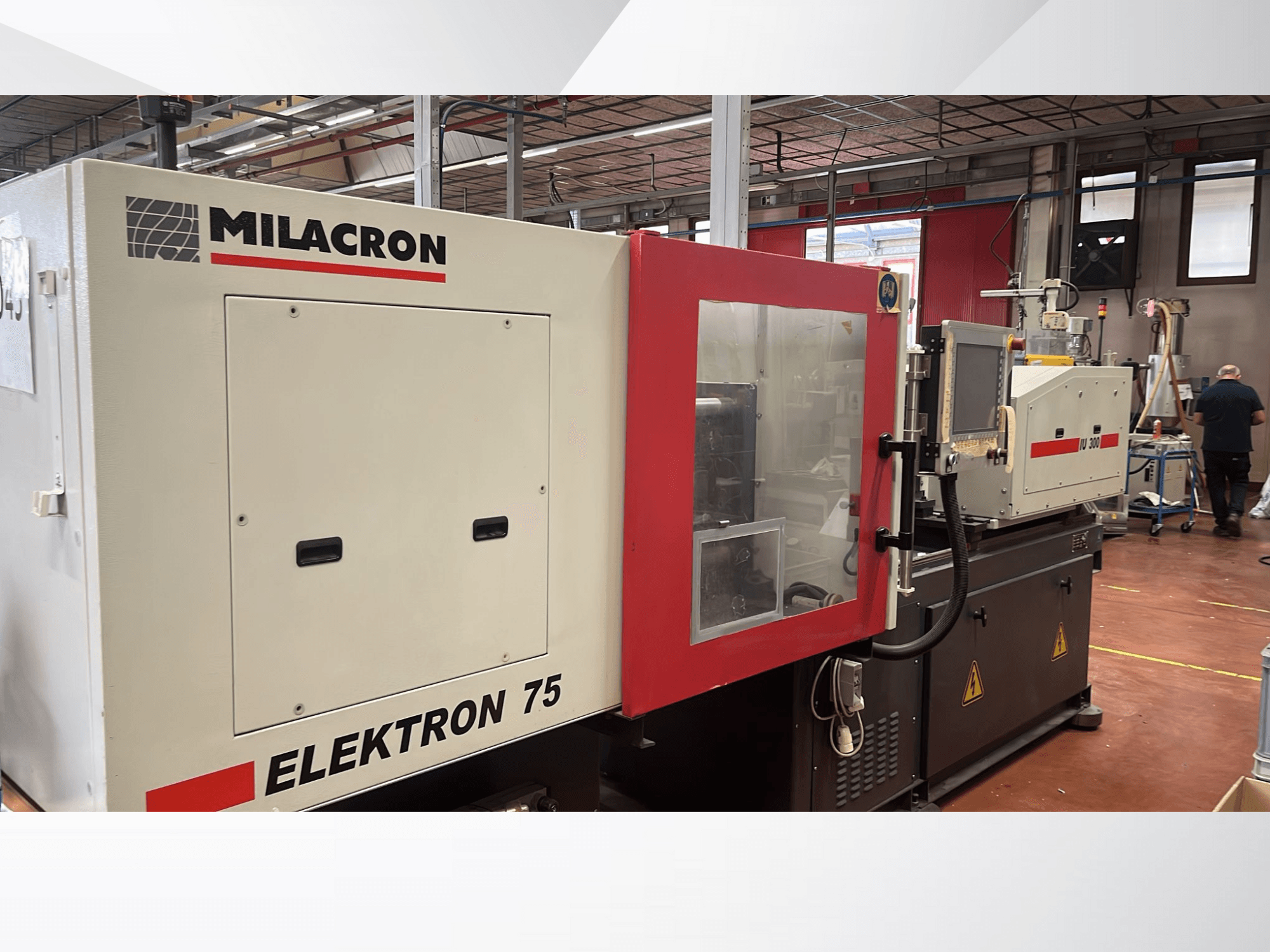 Máquina de moldagem por injeção Milacron Elektron 75 numa oficina, vista lateral mostrando o painel de controlo e as peças mecânicas.