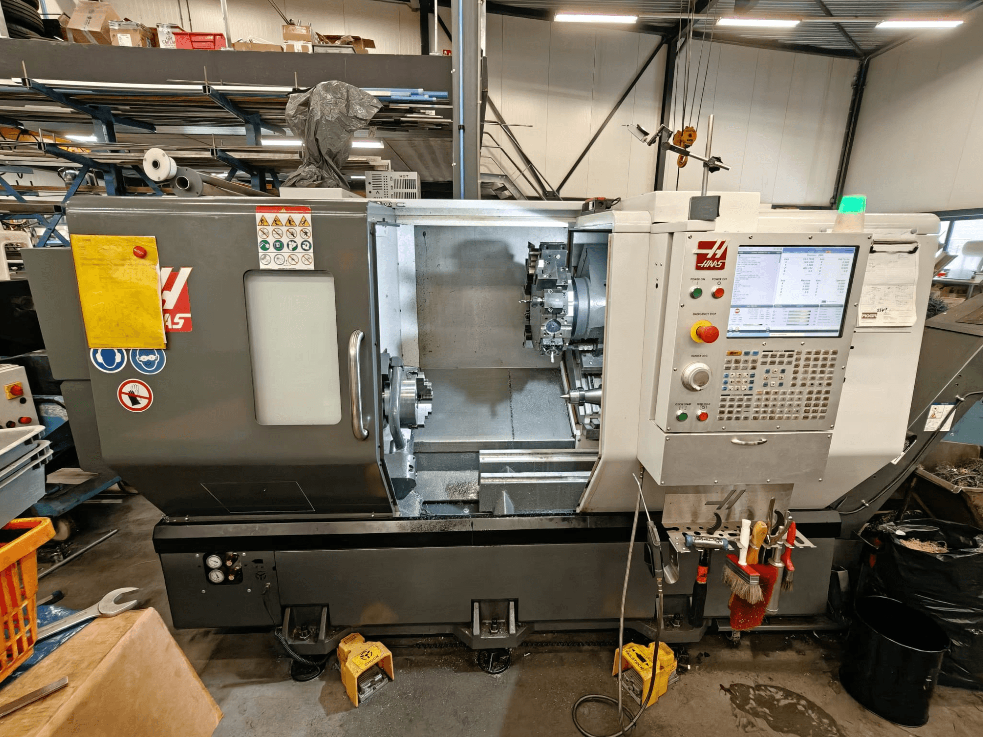 HAAS ST-25Y máquina de torneamento horizontal, vista frontal, mostrando o painel de controlo, armazenamento de ferramentas e configuração operacional na oficina.