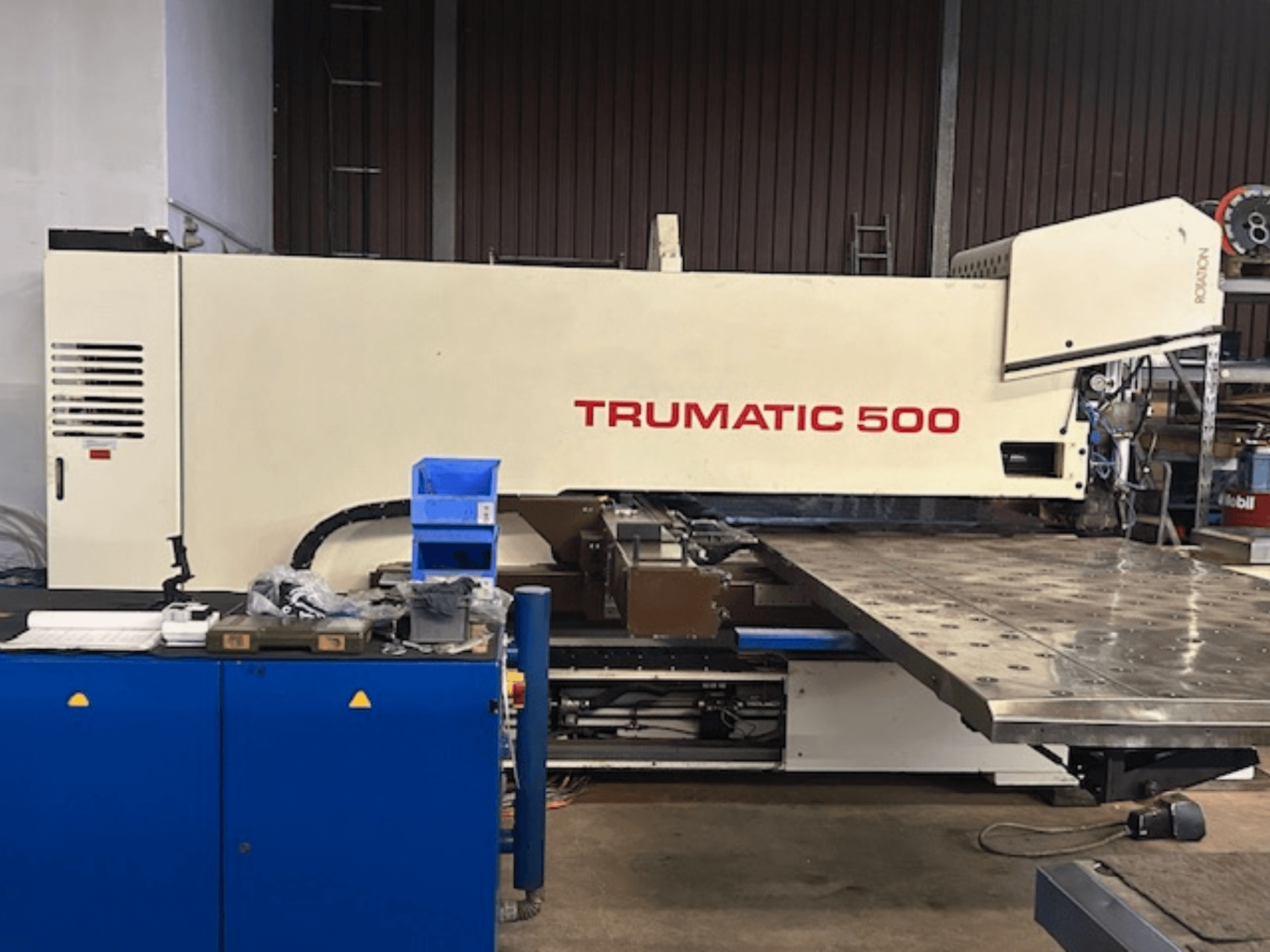 Puncionadora TRUMPF TRUMATIC 500 CNC, vista frontal, com painel de controlo e uma grande mesa de trabalho com superfície perfurada.
