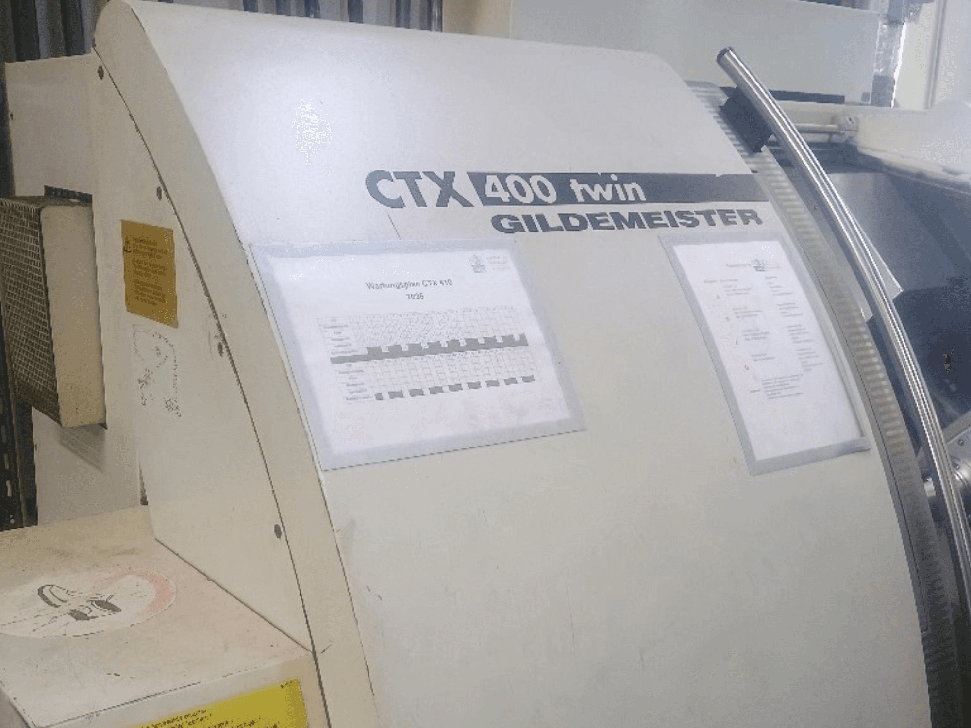 Torno horizontal duplo Gildemeister CTX 400, vista frontal, mostrando os painéis de comando e a documentação técnica.