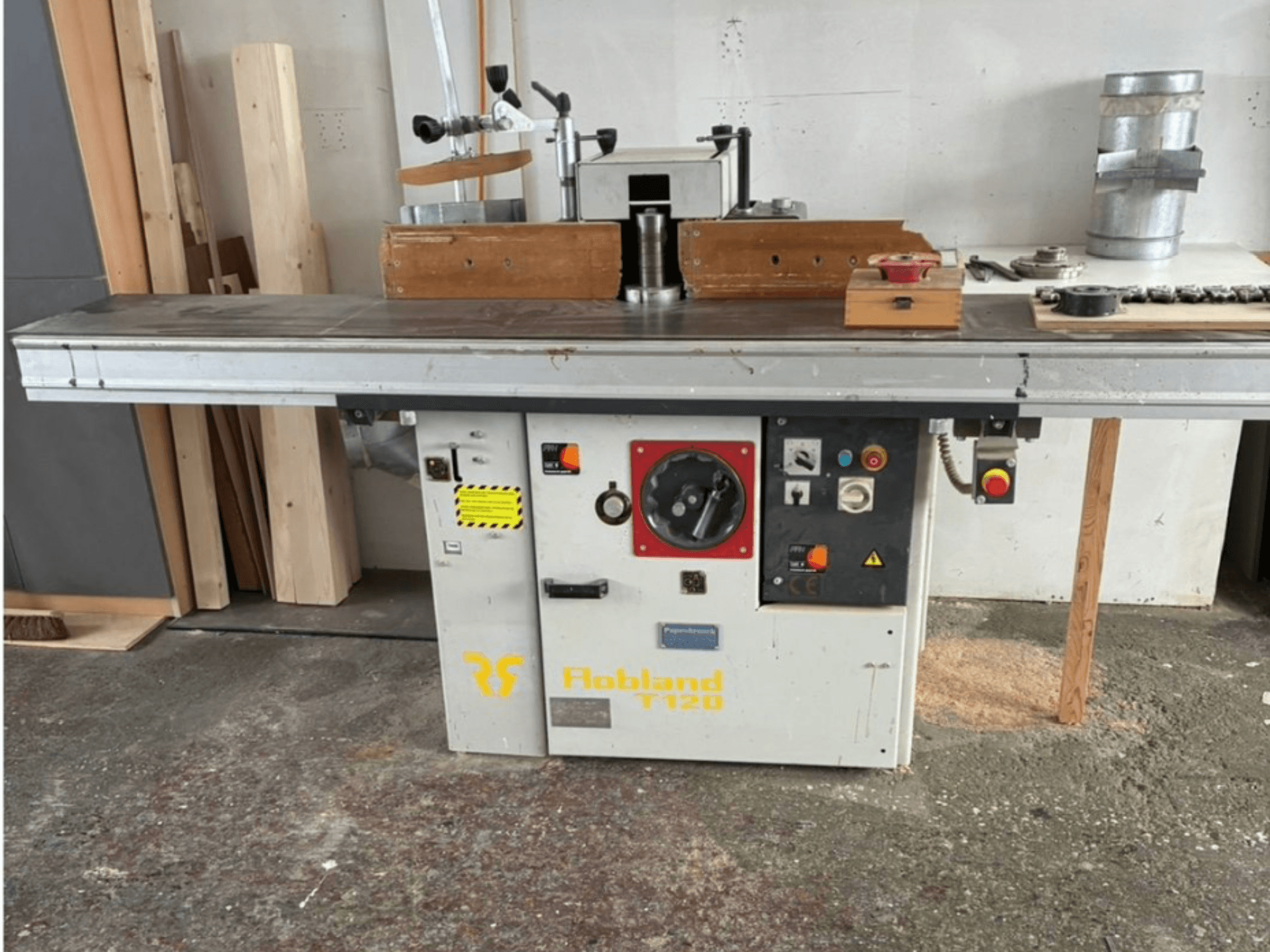 A plaina de mesa Hobbland T120, vista frontal, apresenta uma superfície prateada, painel de controlo com botões e etiquetas de segurança.